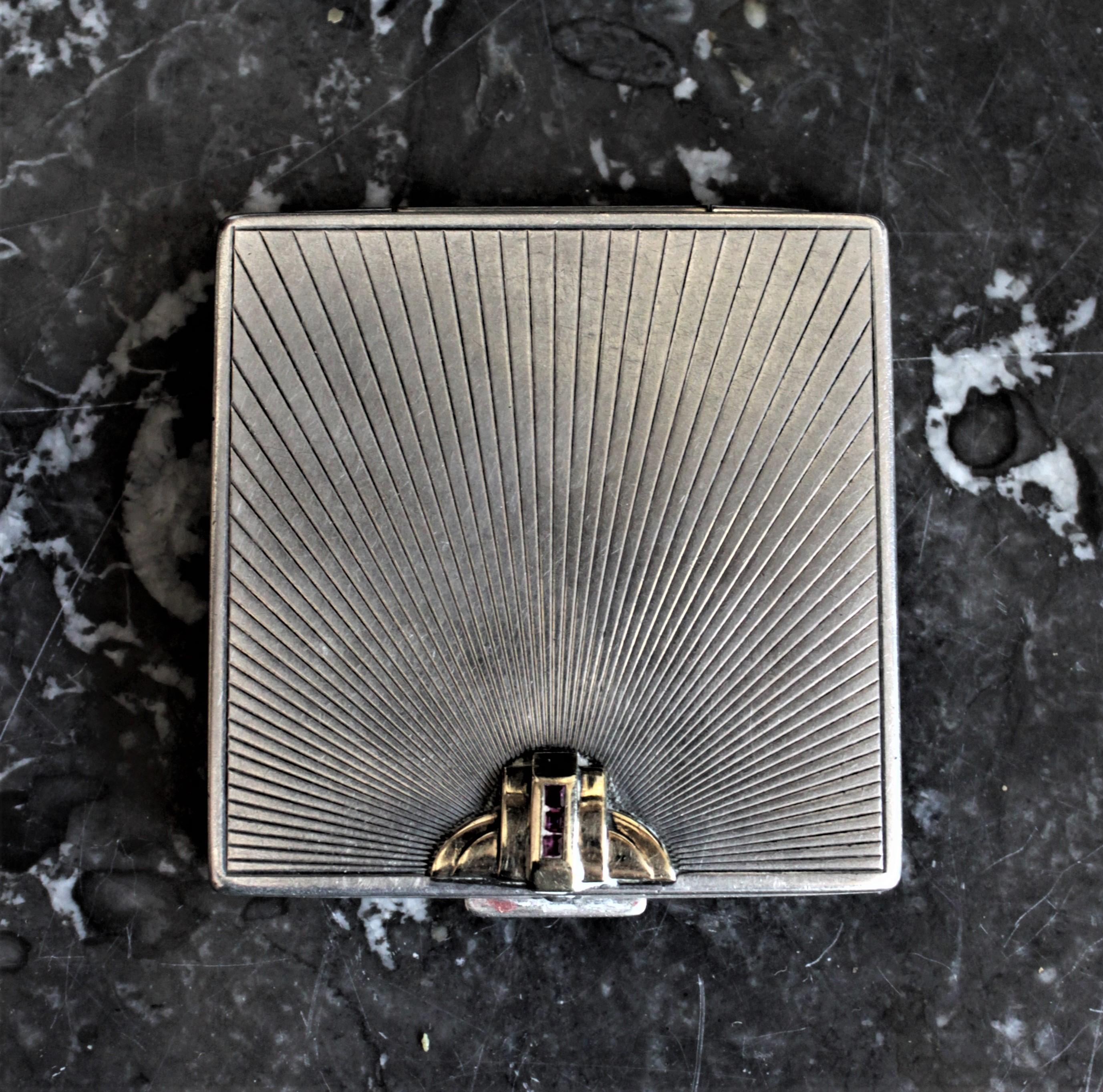This Art Deco sterling silver and 14-karat yellow gold ladies compact was made in England during the 1930s, by Black, Starr & Gorham. The compact has an engraved case done in a typical Art Deco styled linear fashion with a stepped Deco 14-karat
