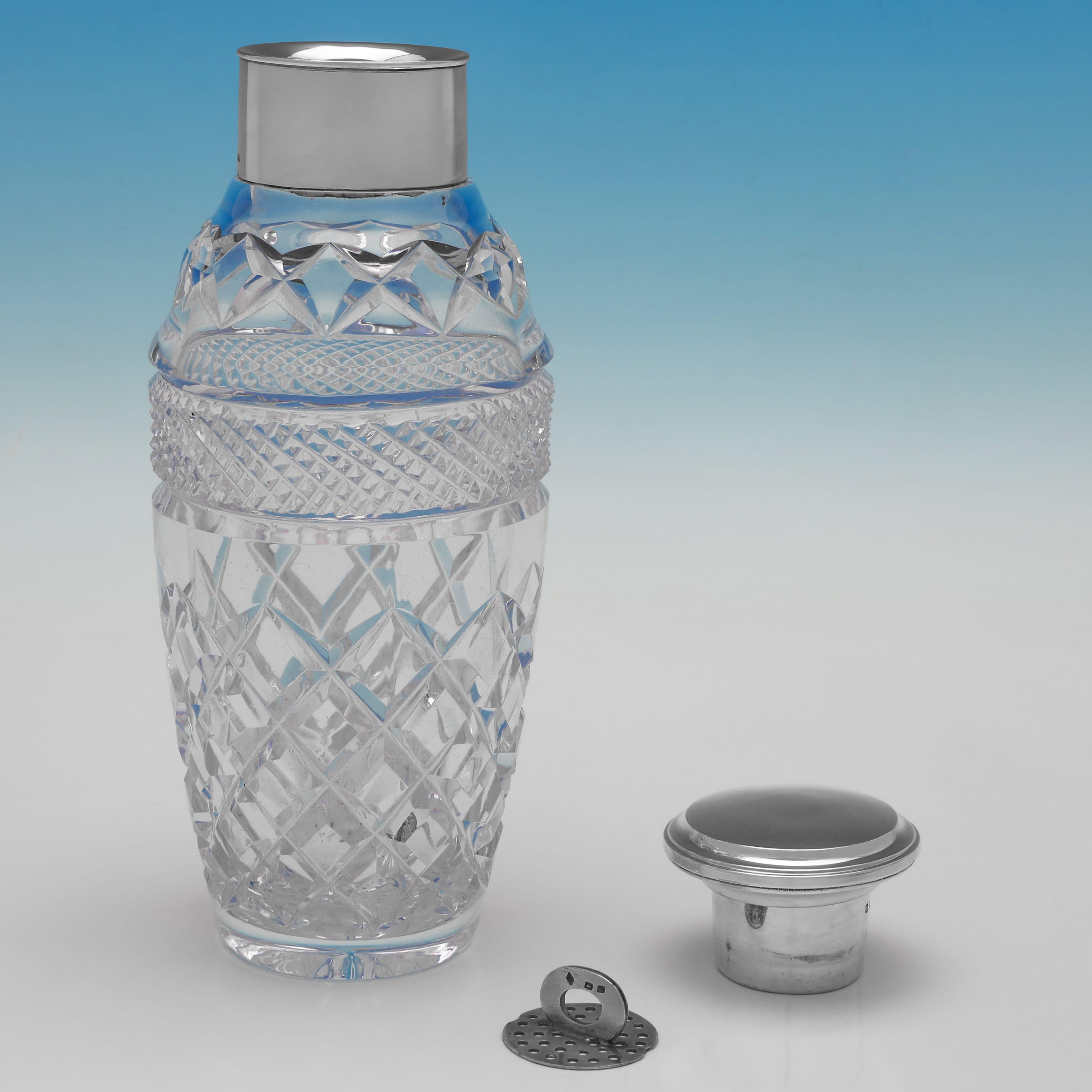 Hallmarked in Birmingham in 1927, this stylish, George V, Sterling Silver & Glass Cocktail Shaker, features a cut glass body and a plain silver mount, lid and removable strainer. The cocktail shaker measures 9