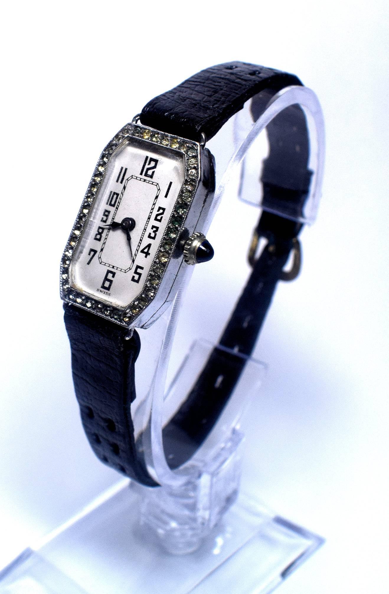 This is stylish 1930s authentic Art Deco cocktail watch sterling silver set with tiny little diamonds around the edge of crystal and a small blue gemstone set into winder at side. The dial is in excellent condition with just the tiniest of signs of