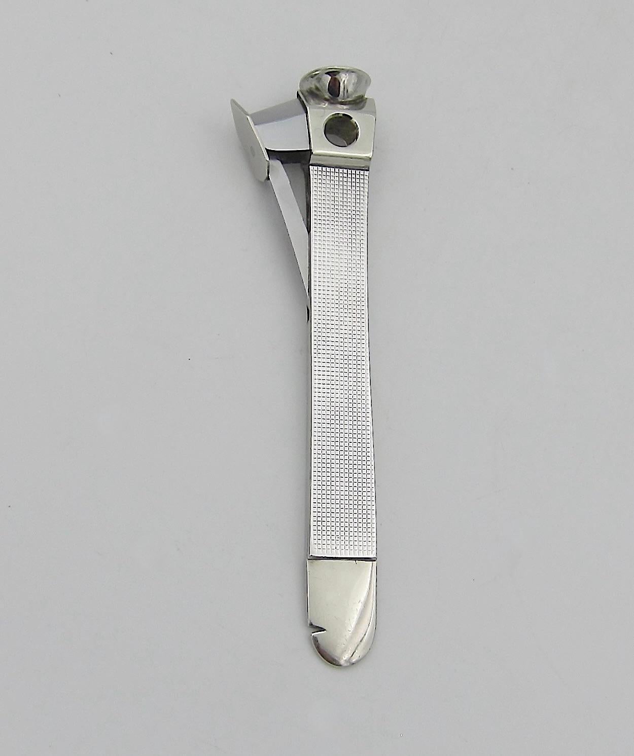 A vintage sterling silver mounted cigar, cheroot, or cigarillo cutter incorporating a German steel blade. The slim and elegant sterling silver handle is decorated on either side with delicate Art Deco lines forming a grid pattern. The cutter has a