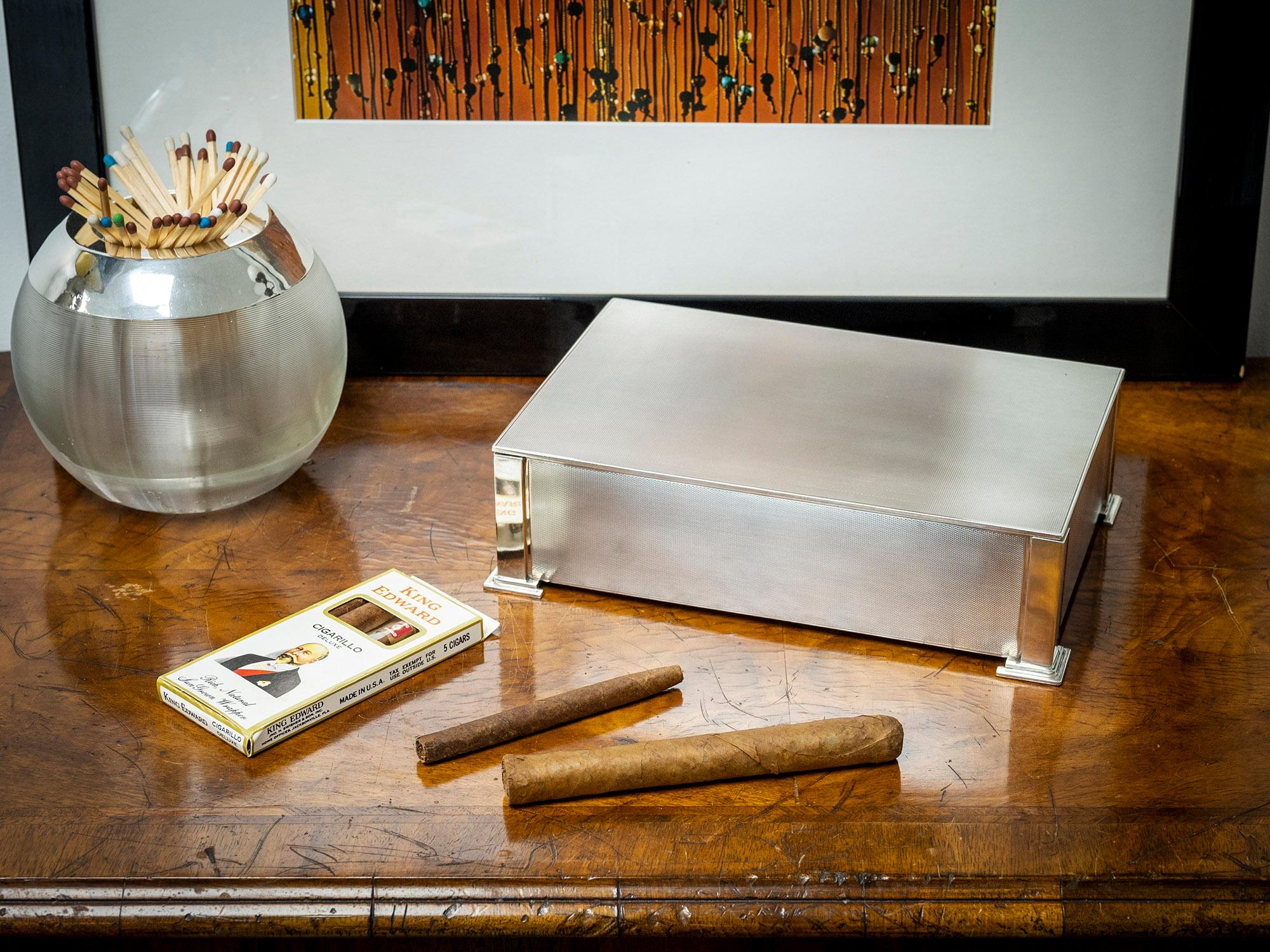 Mit Zedernholzauskleidung

Wir freuen uns, Ihnen diese Art Deco Sterling Silber Zigarrenkiste aus unserer Silver Collection anbieten zu können. Die Zigarrenkiste in rechteckiger Form aus Sterlingsilber verfügt über gedrechselte Paneele mit