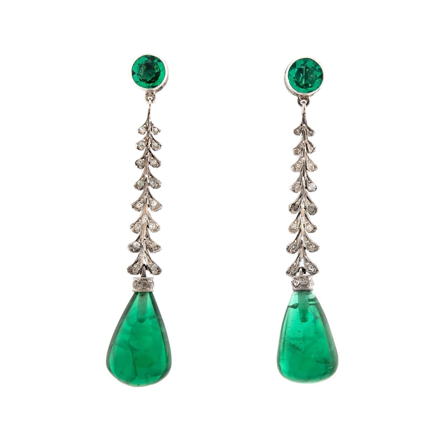 A beautiful and vibrant pair of earrings from the Art Deco (ca1920s) era! Crafted in sterling silver, each earring begins with a circular, bezel-set synthetic emerald surmount. The earring then feature a flexible link, which resembles interlocking