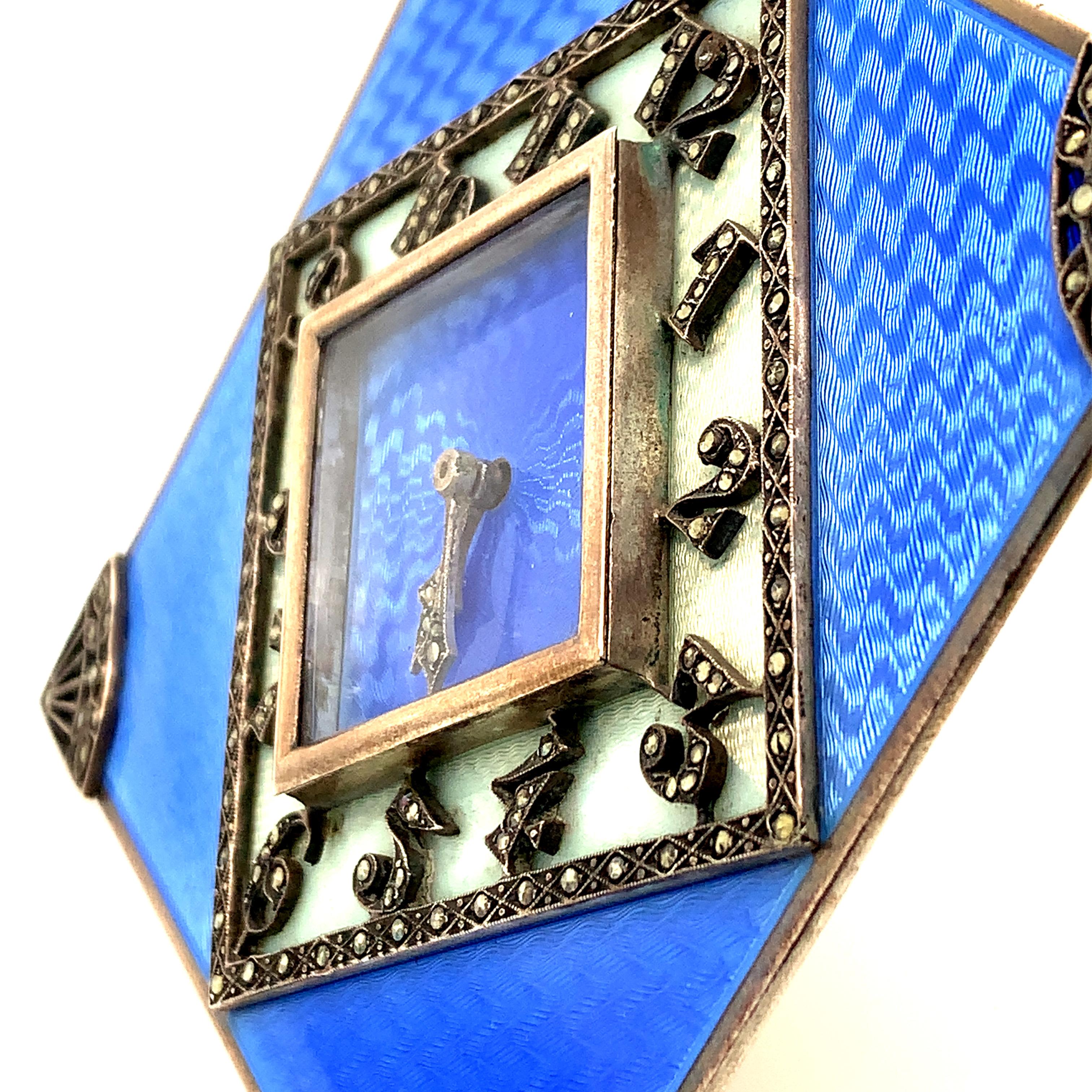 Exquisite art deco clock.  Sterling silver with brilliant blue guilloche enamel.  The diamond-shaped reserve in the center has marcasite numerals.  Applied sterling corners are also set with marcasites.  Mechanical works.  3