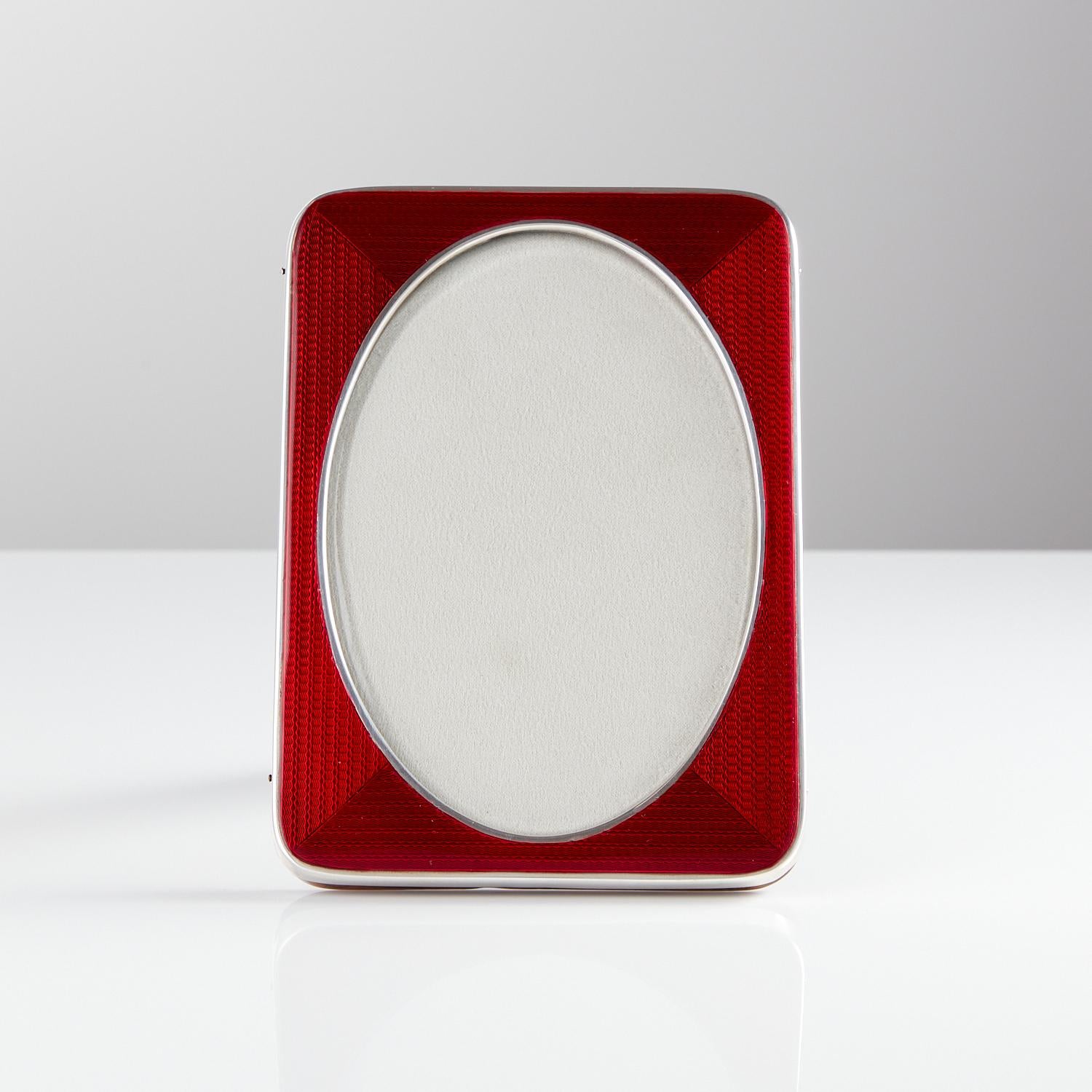 Art Deco sterling silver & enamel picture frame, Birmingham 1921.

An extraordinary art deco sterling silver and enamel picture frame, by Sanders & Mackenzie. Consisting of a beautiful bold and translucent coloured red enamel frame and english oak