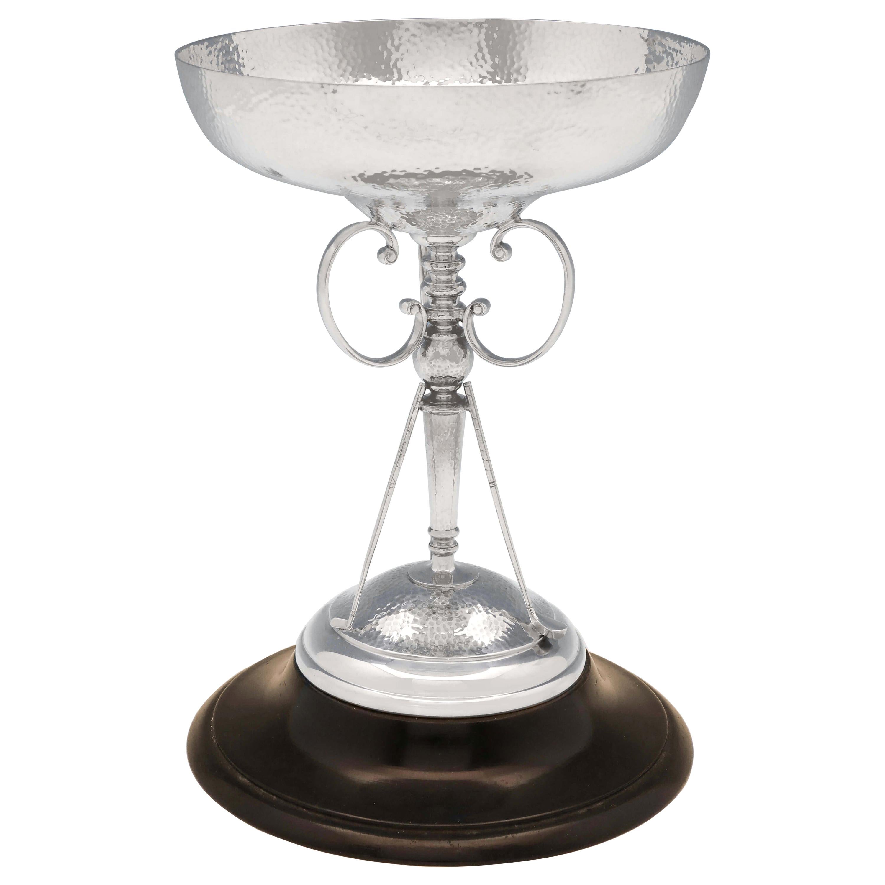 Hallmarked in Sheffield in 1930 by R. F. Moseley & Co., this fantastic, George V, Art Deco, sterling silver golf trophy, features a hand hammered finish, the original wooden plinth, and three golf clubs sporting the central column. The golf trophy