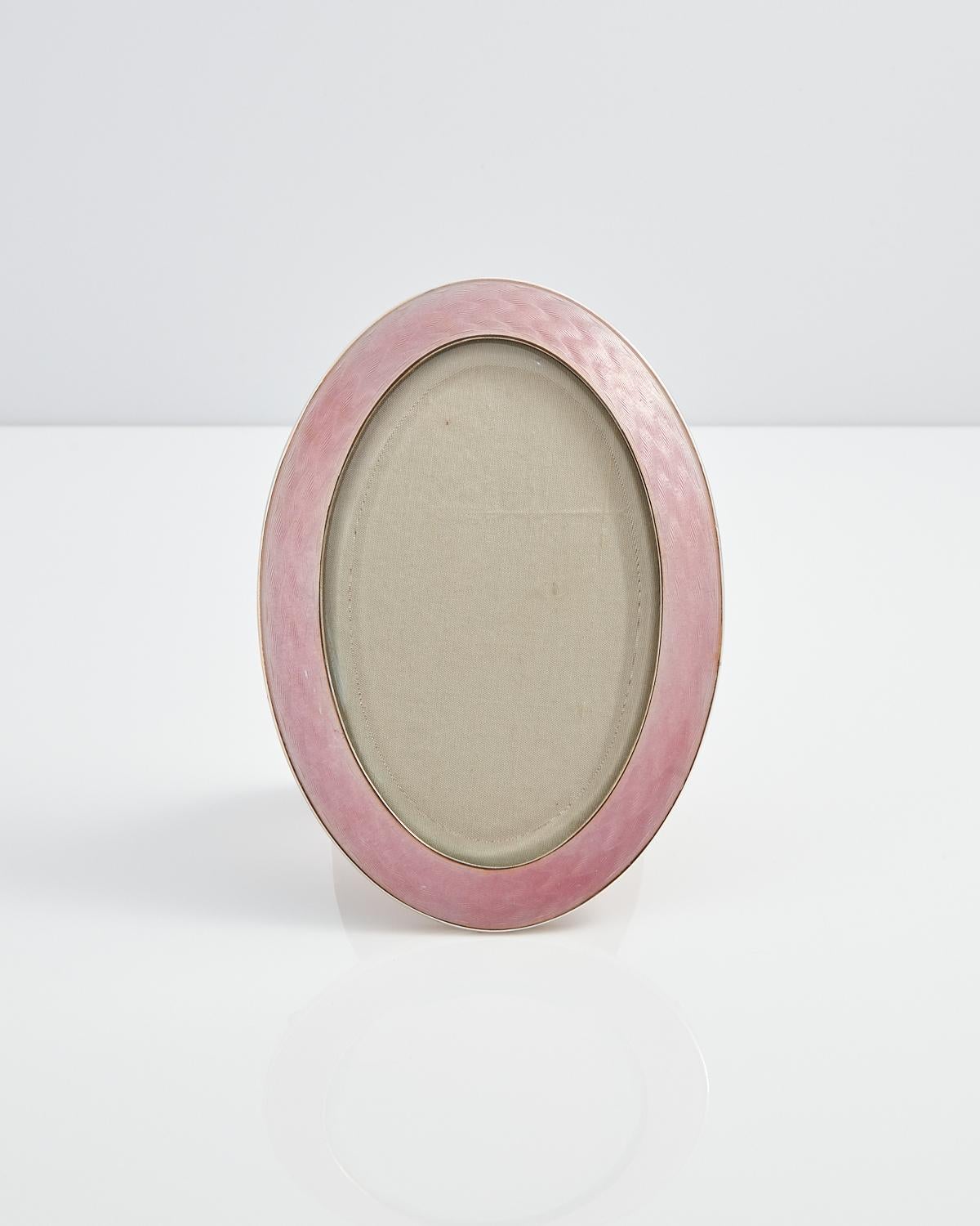 A beautiful Art Deco Sterling Silver & Guilloche enamel Picture Frame, Circa 1920, Origin Denmark.

A superb quality heavy gauge silver & enamel picture frame.

The muted soft pink translucent enamel is in perfect condition. The oak back and easel