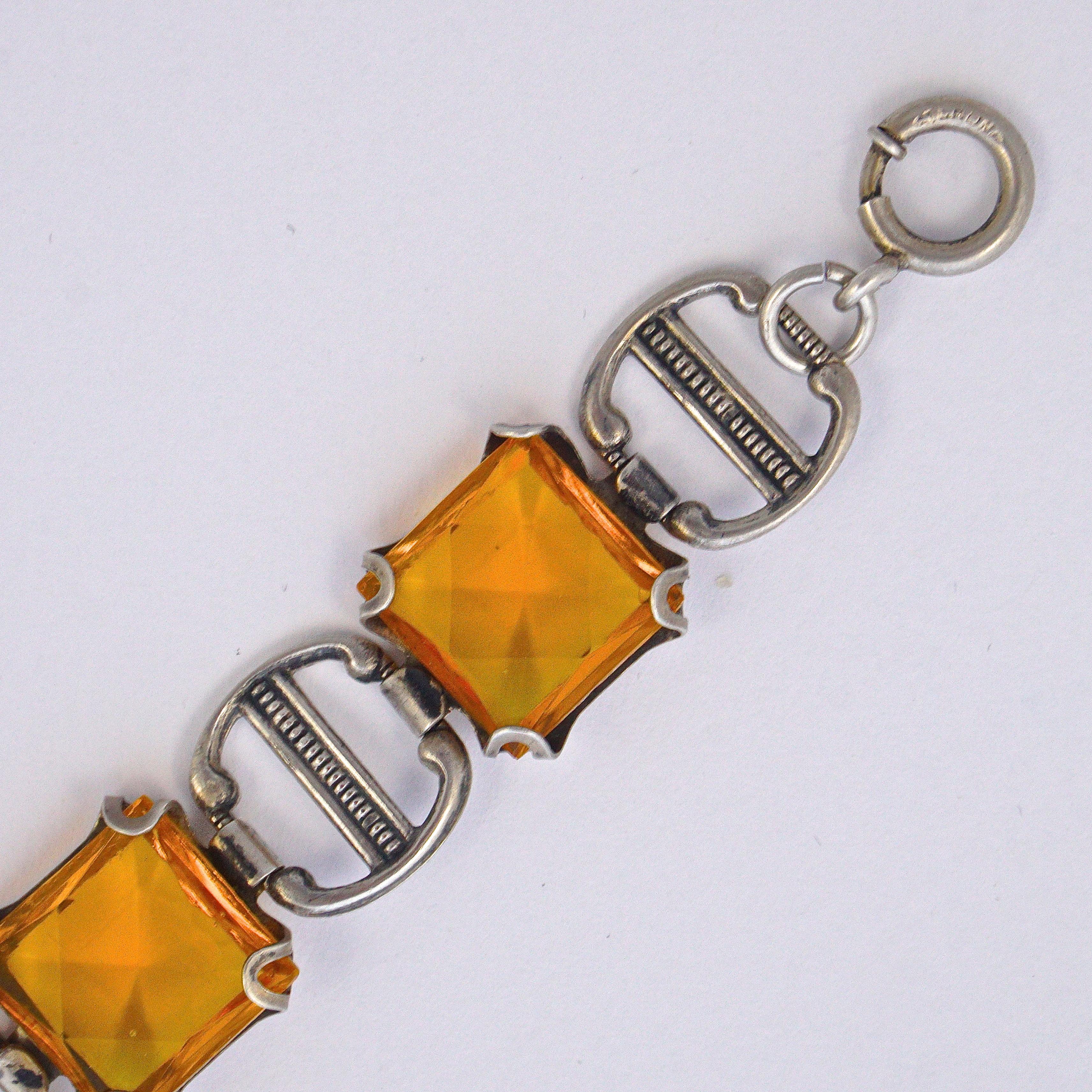 Stylish Art Deco sterling silver link bracelet, featuring lovely amber glass stones in open back settings. There is a spring bolt clasp which is marked Sterling, and the bracelet tests for silver. The faceted glass stones are raised at the front and