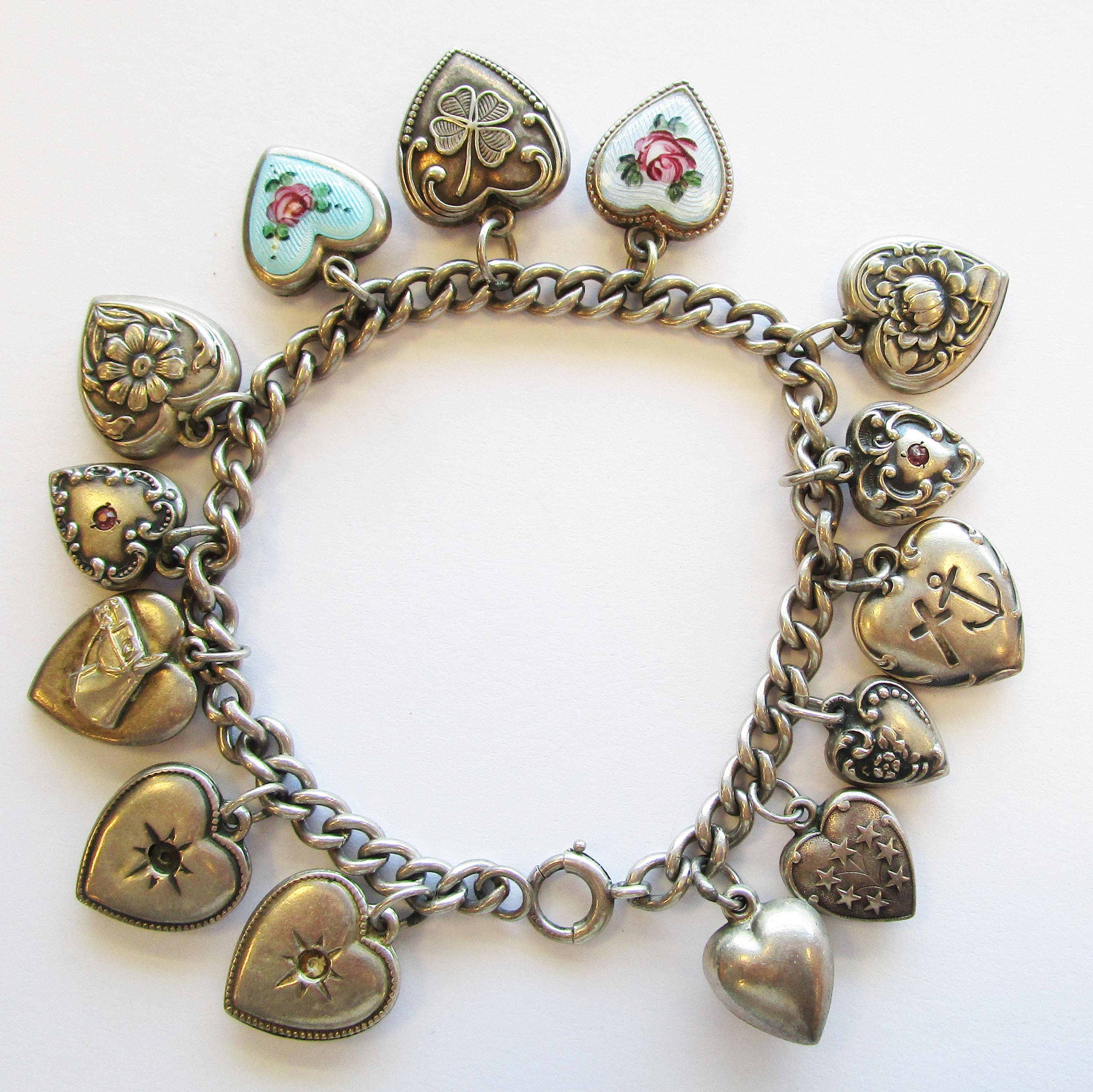 This is a beautiful vintage sterling silver puffy heart charm bracelet from the Art Deco era. The bracelet has a total of fourteen beautiful heart charms, two of which are enameled with gorgeous flowers! This is the perfect bracelet for someone who
