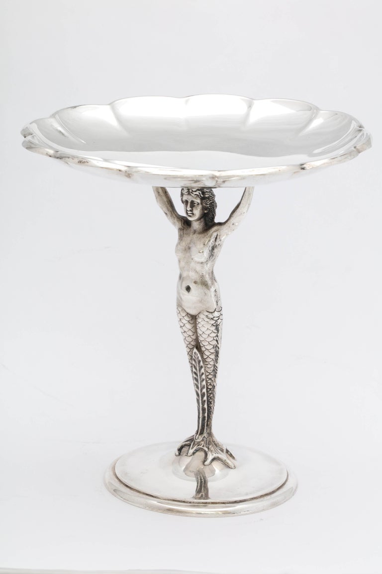 Art Deco, sterling silver, figural tazza, Reed and Barton, Taunton Mass., year hallmarked for 1933, having a full-bodied mermaid (as its stem) supporting a scalloped bowl. Measures: 6 3/4 inches high x over 6 1/4 inches in diameter. Weighs 10.875