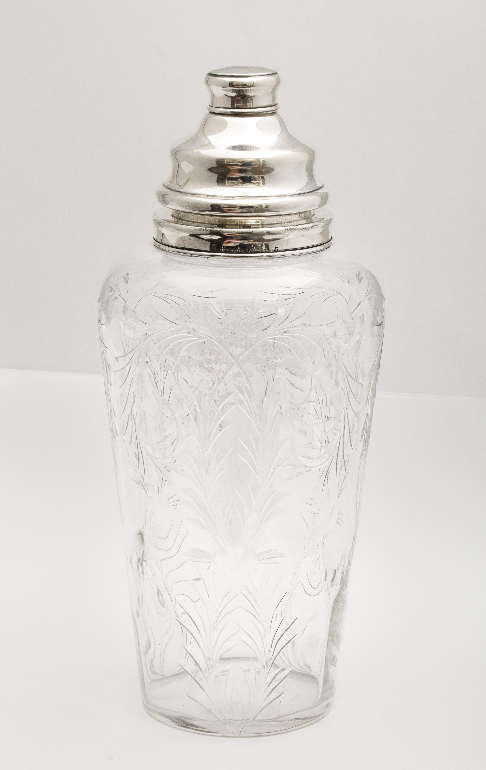 Art Deco, sterling silver-mounted, wheel cut glass cocktail shaker, T.G. Hawkes & Company, New York, Ca. 1930's. Measures 9 1/2 inches high (at highest point) x 5 inches diameter. Glass is signed with the company logo (three hawks) on underside of