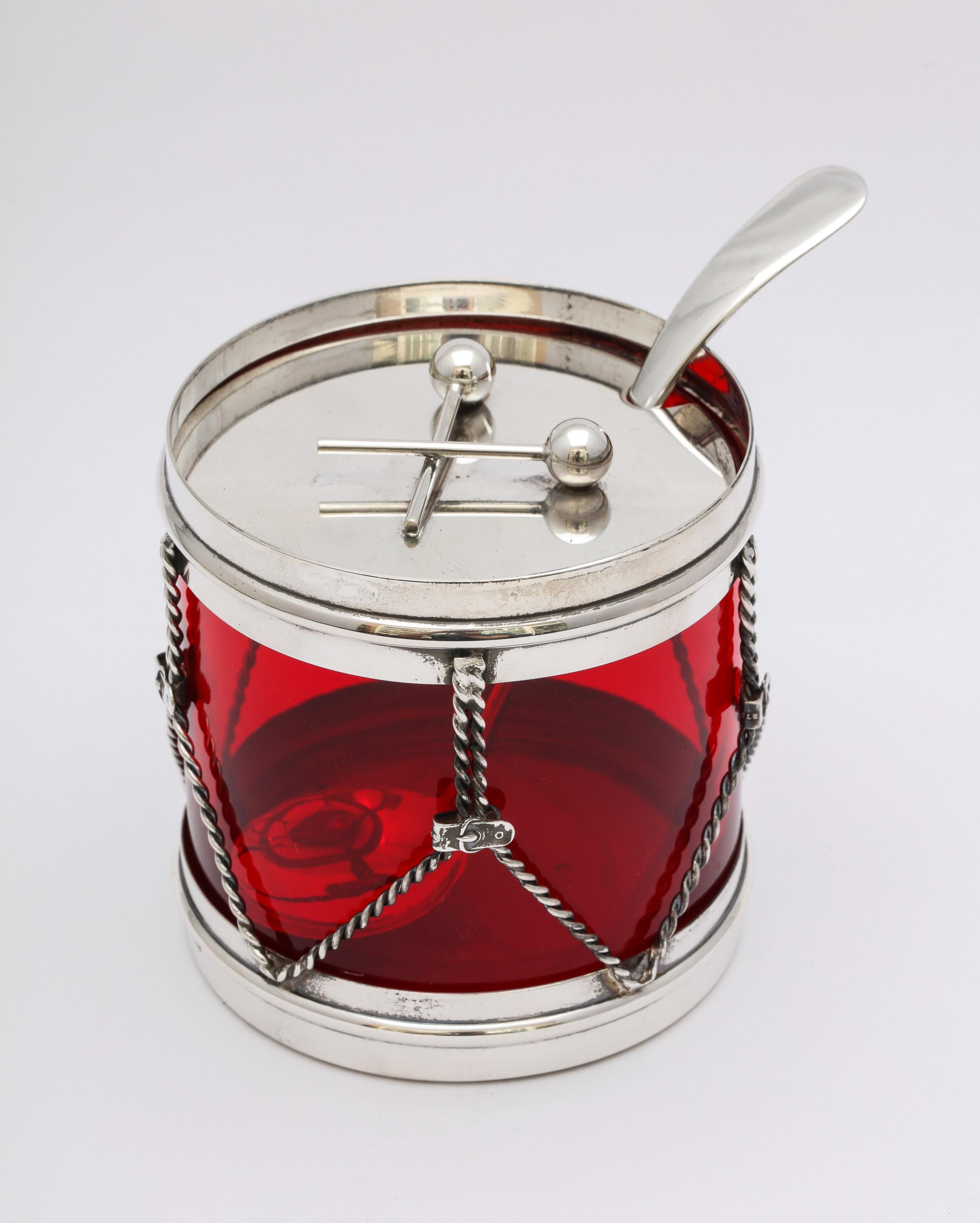 Art Deco, sterling silver-mounted red glass, drum-form condiments jar with original spoon, R. Blackinton and Co., No. Attleboro, Mass, circa 1930s. Crossed drumsticks serve as a handle to lift sterling silver lid. Red glass liner is removable.