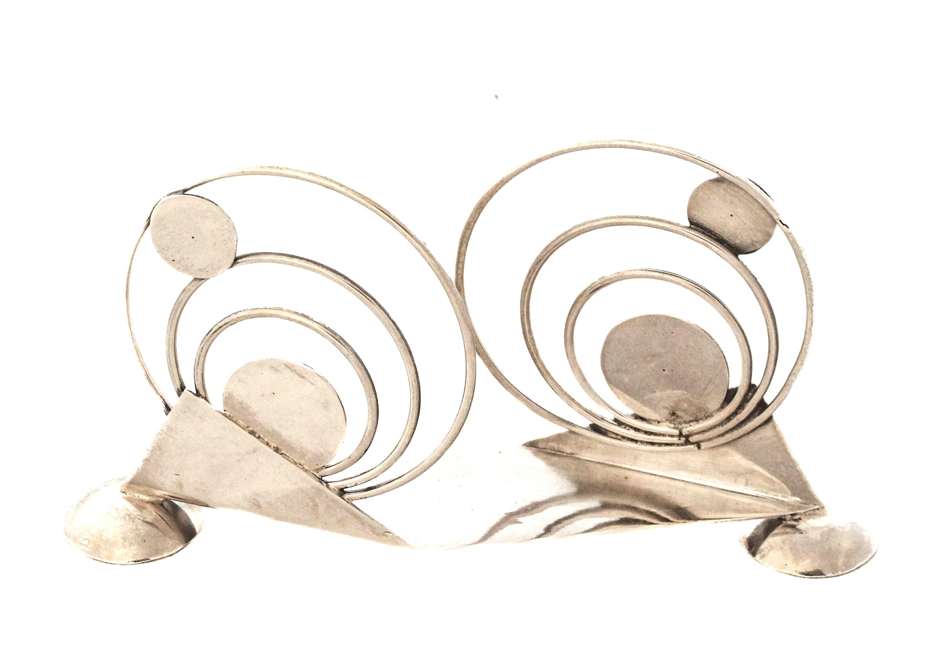 In offerta c'è un portatovaglioli in argento sterling unico nel suo genere, risalente agli anni Venti.  Ha un design distintivo che, grazie all'uso di forme diverse, ricorda le opere di Wassily Kandinsky.  Presenta linee decise e forme insolite che