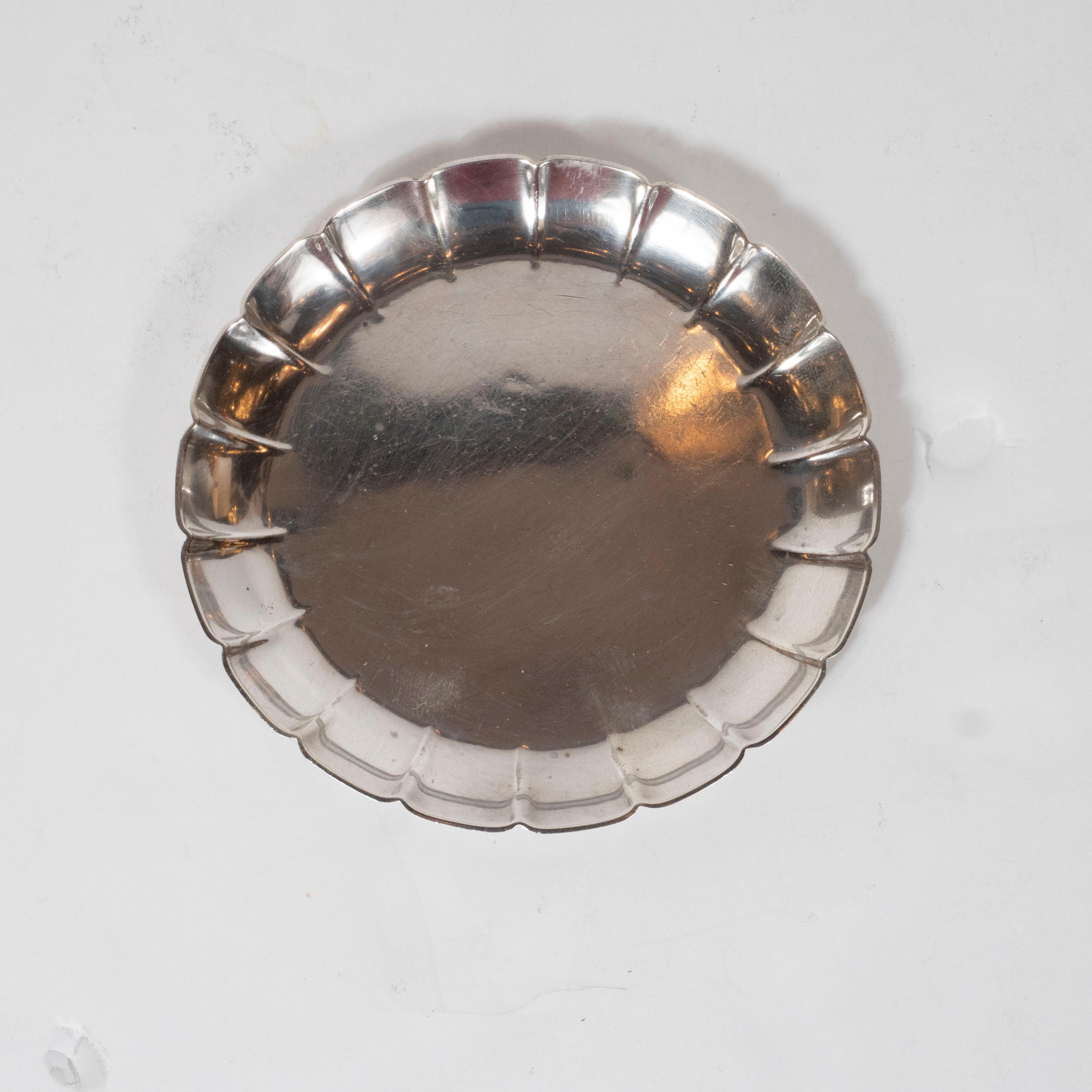 This elegant Art Deco sterling silver dish was realized by the esteemed American maker Tiffany & Co., circa 1920. It features a round body with raised and scalloped sides, separated by ridges in relief. With its beautiful quality and clean modernist