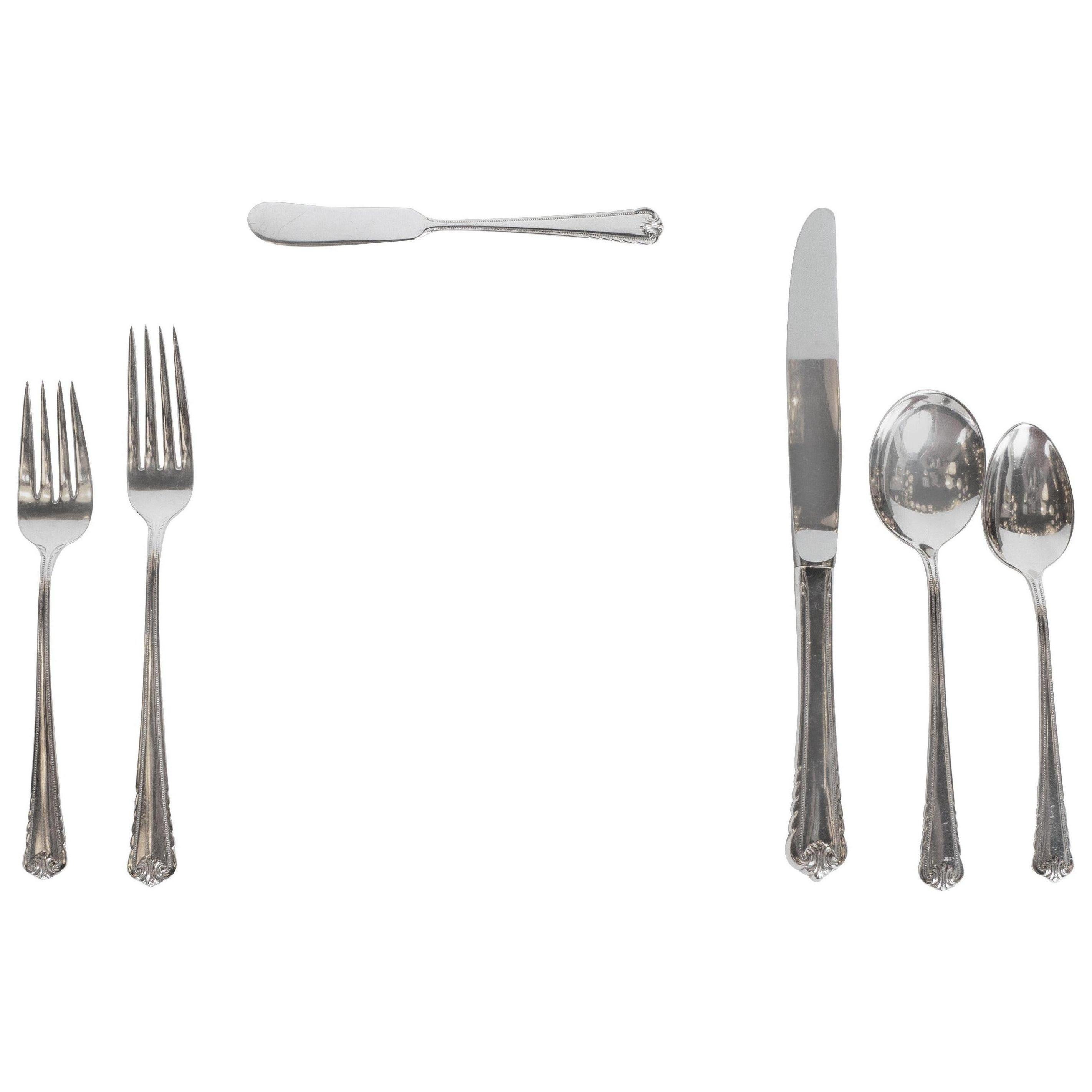 This beautiful Art Deco sterling silver set, realized in a neoclassical style, is a complete set for eight guests, including eight of the following: soup spoons, butter knives, tea spoons, salad forks, as well as dinner knives and forks. All feature