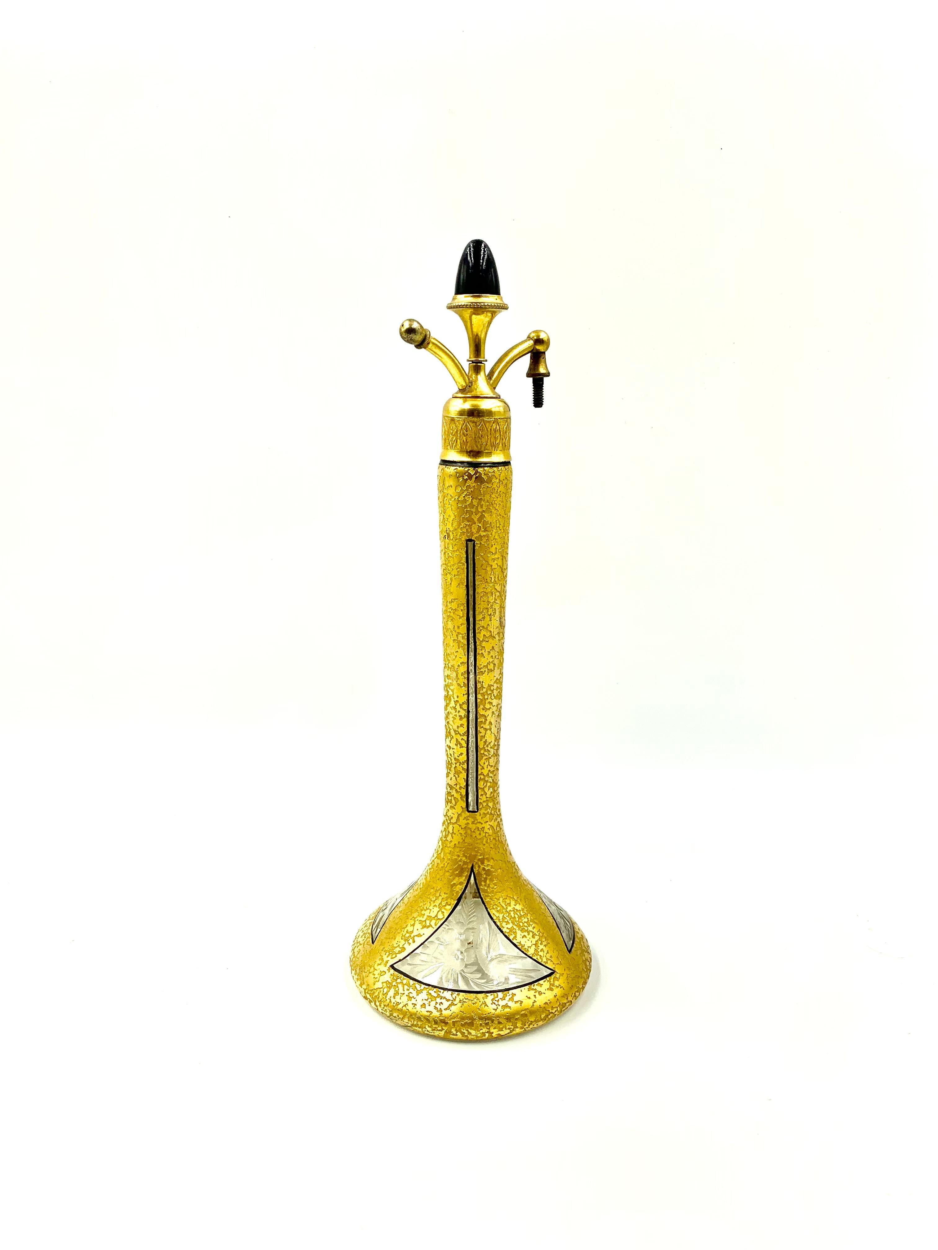 International Perfume Bottle Association lists this beautiful 10 inch tall perfume bottle as a Steuben glass piece decorated by DeVilbiss with an enameled gold surface, three engraved triangular windows with floral and bird decoration and a black