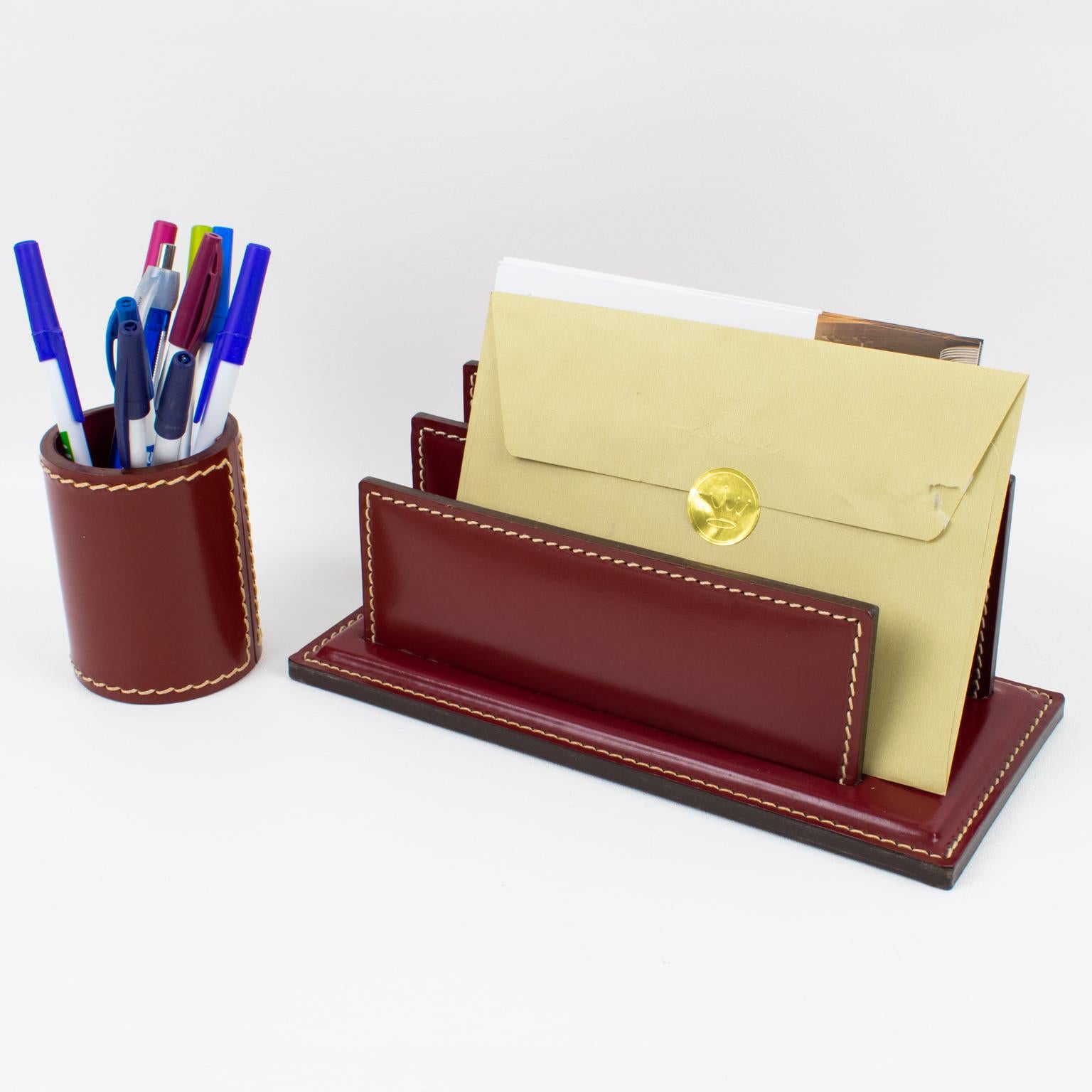 ILG, Belgium, designed a functional modernist desk accessories set in the 1940s. The set includes a letter and pen holder, featuring a streamlined shape and boasting burgundy-red hand-stitched leather. This gorgeous addition will bring a touch of