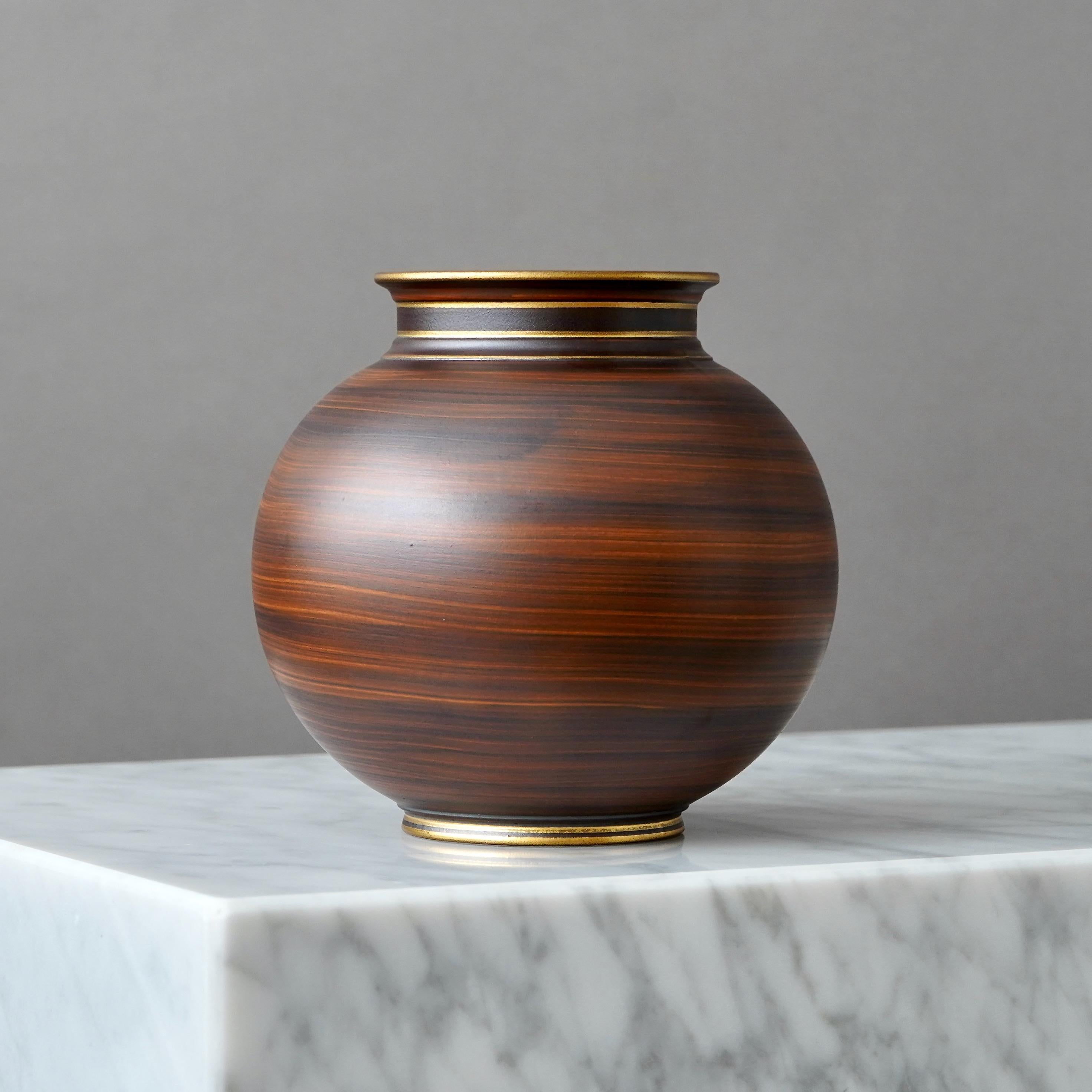 Vase art déco en grès avec une belle glaçure brune. La fièvre aphteuse détaillée en or.
Conçu par Gunnar Nylund pour ALP (Lidköpings Porslinsfabrik), Suède, années 1930.

Excellent état.
Estampillé 