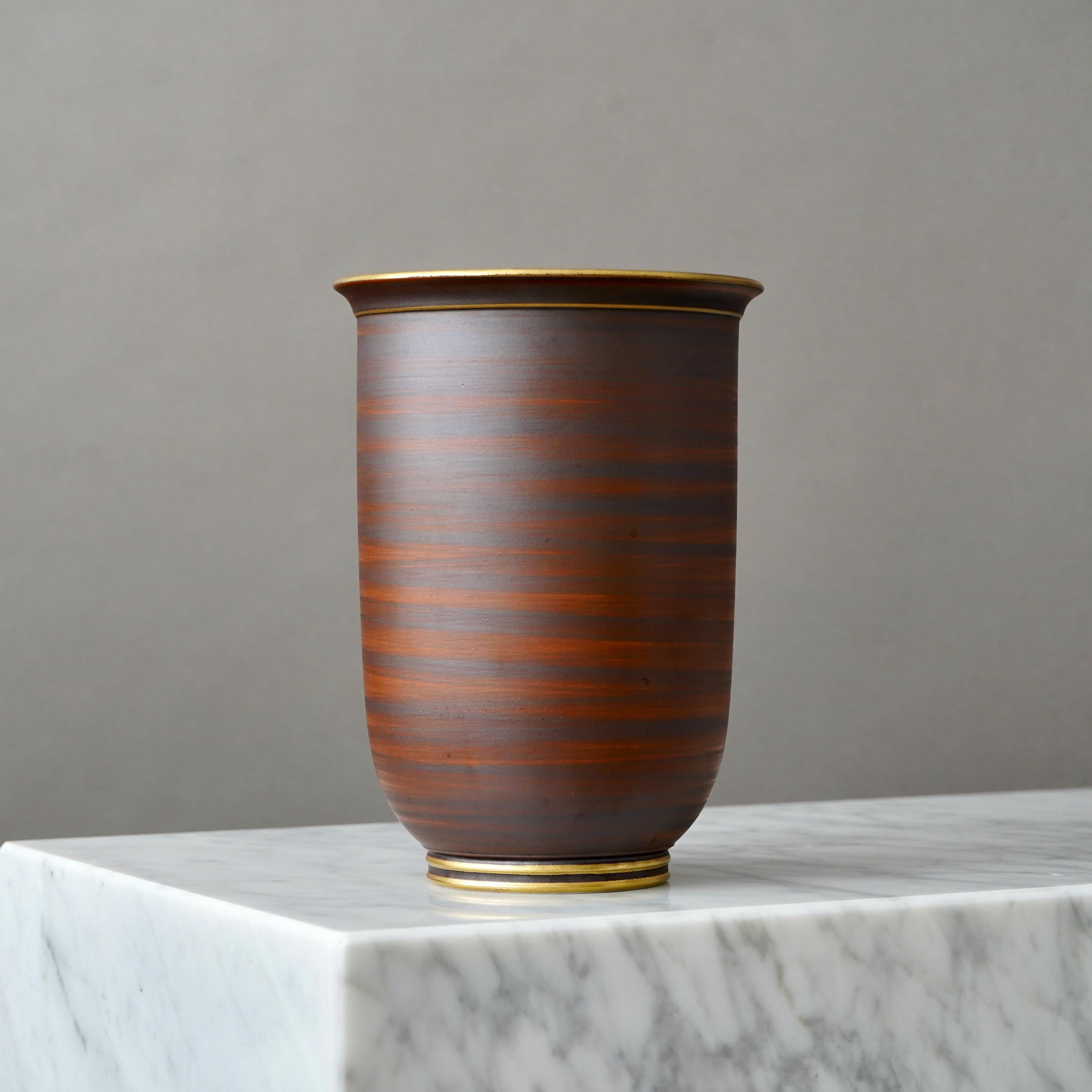 A stoneware art deco vase with beautiful brown glaze. Foot and mouth detailed in gold.
Designed by Gunnar Nylund for ALP (Lidköpings Porslinsfabrik), Sweden, 1930s.

Excellent condition.
Stamped 'ALP', 'Modell Nylund', 'Lidköping, SWEDEN' and