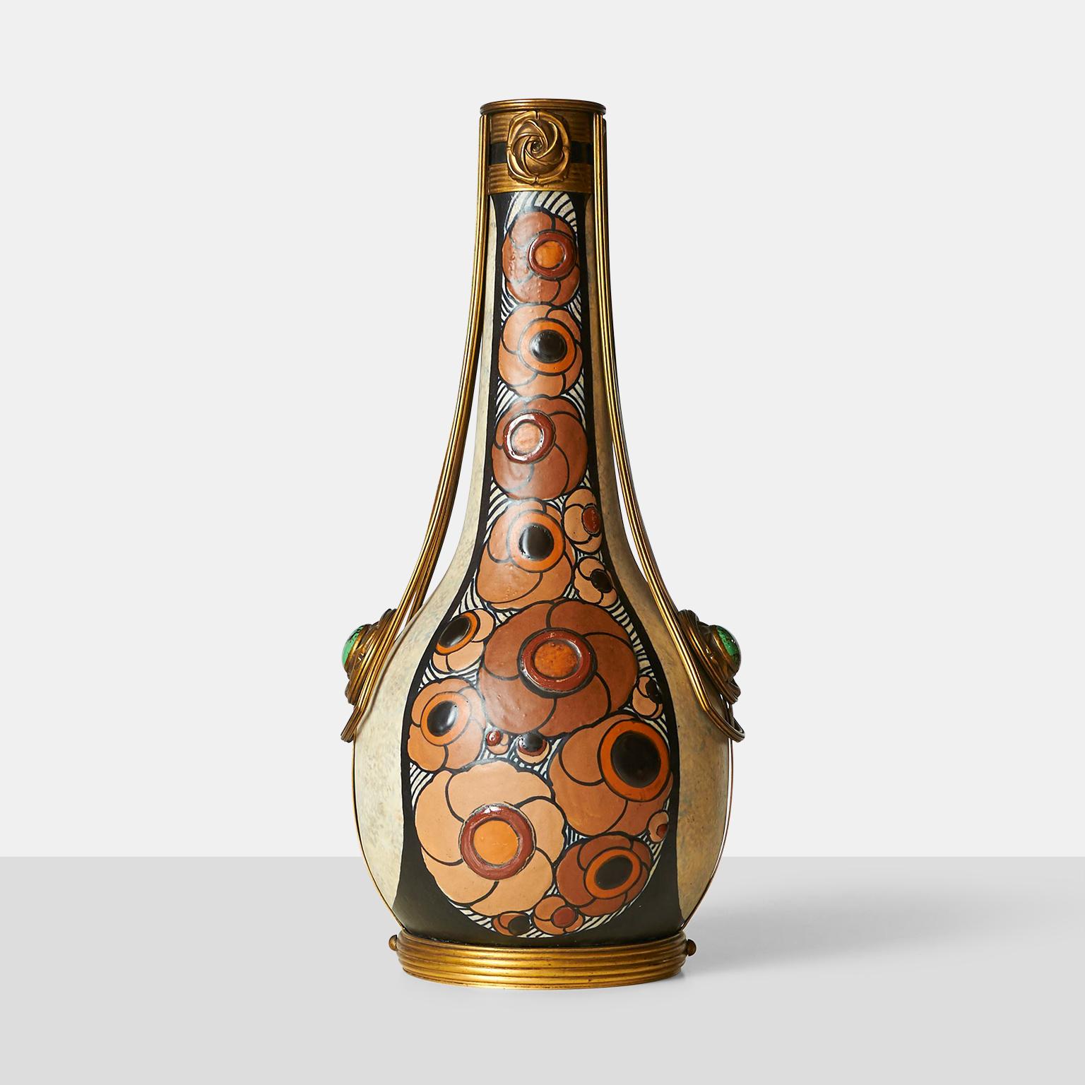 An Art Deco ovoid-shaped stoneware vase enameled bluish-beige with orange brown and black floral motifs by French sculptor Luis Auguste Dage. Gilded bonze mounting adorned with green cabochons. Signed 
