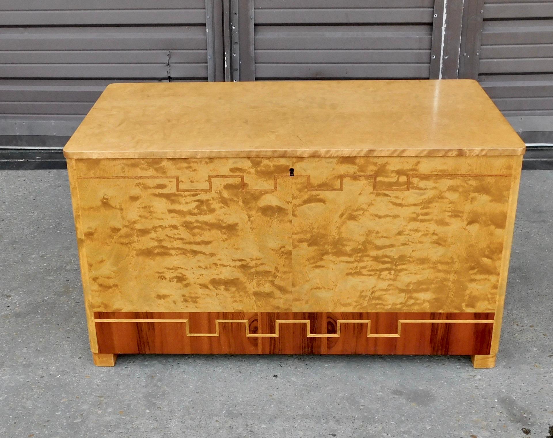 Rare Swedish art deco storage chest rendered in highly figured golden flame birch and banded with rosewood. Greek key type inlay in elm. 
This piece is in excellent original condition with finish in good condition and all the wood joinery