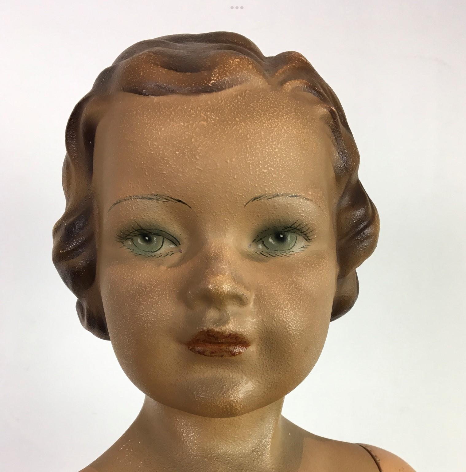 Art Deco store display doll - child mannequin doll.
This antique child mannequin is a girl. 
She has a painted plaster body, painted eyes and a painted wooden base. This store display advertising doll is probably designed for a clothing line which