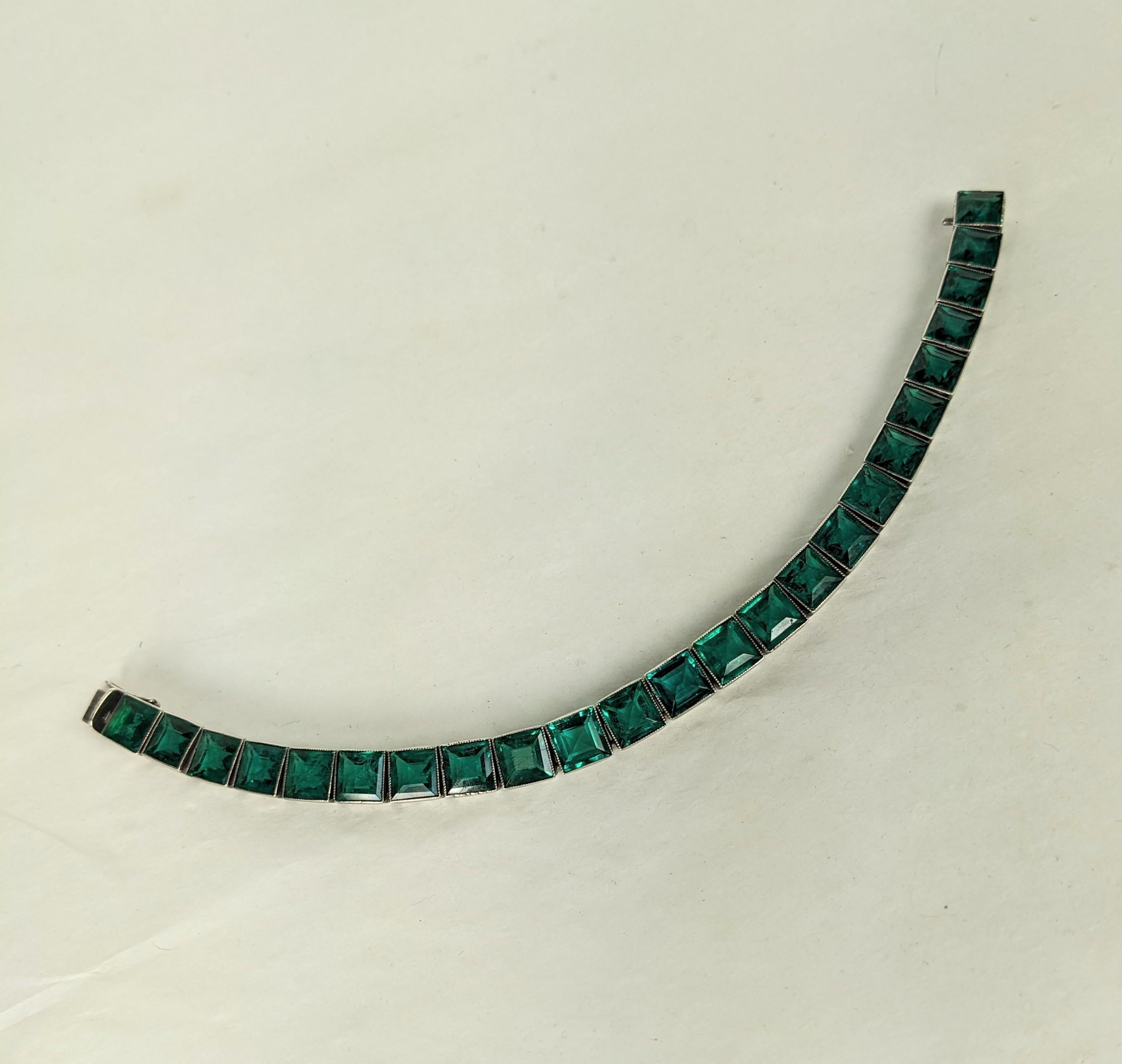 Attractive Art Deco Straight Line Emerald Bracelet set in sterling from the 1930's. High quality manufactured Deco bracelet with etched shoulders and emerald pastes in serrated settings with molded inclusions to replicate real stones. Lesser quality