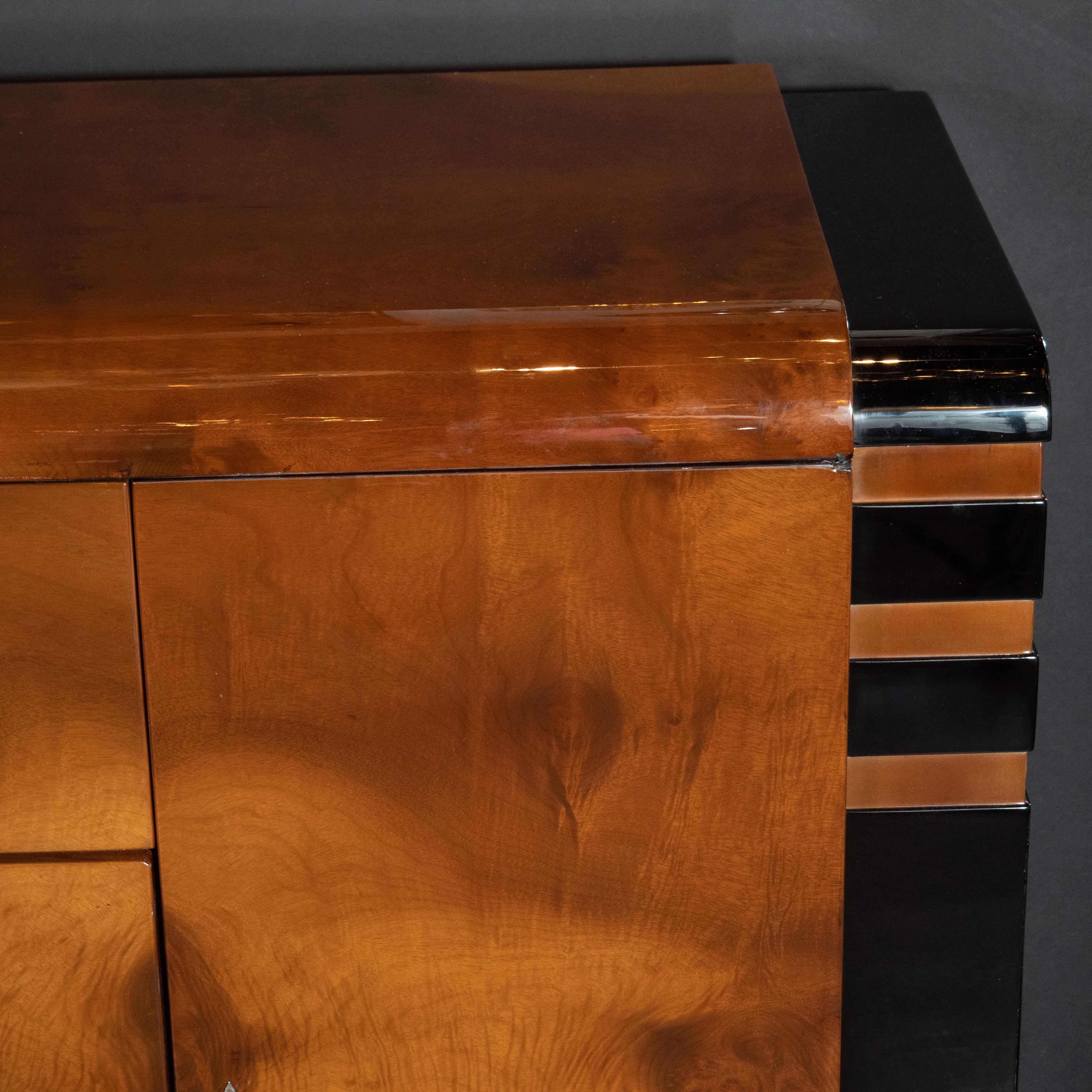 This stunning Art Deco Machine Age sideboard was designed by the 20th century luminary behind Radio City Music Hall, Donald Deskey, circa 1935. Executed in burled walnut- replete with a stunning natural grain- and black lacquer with brushed aluminum