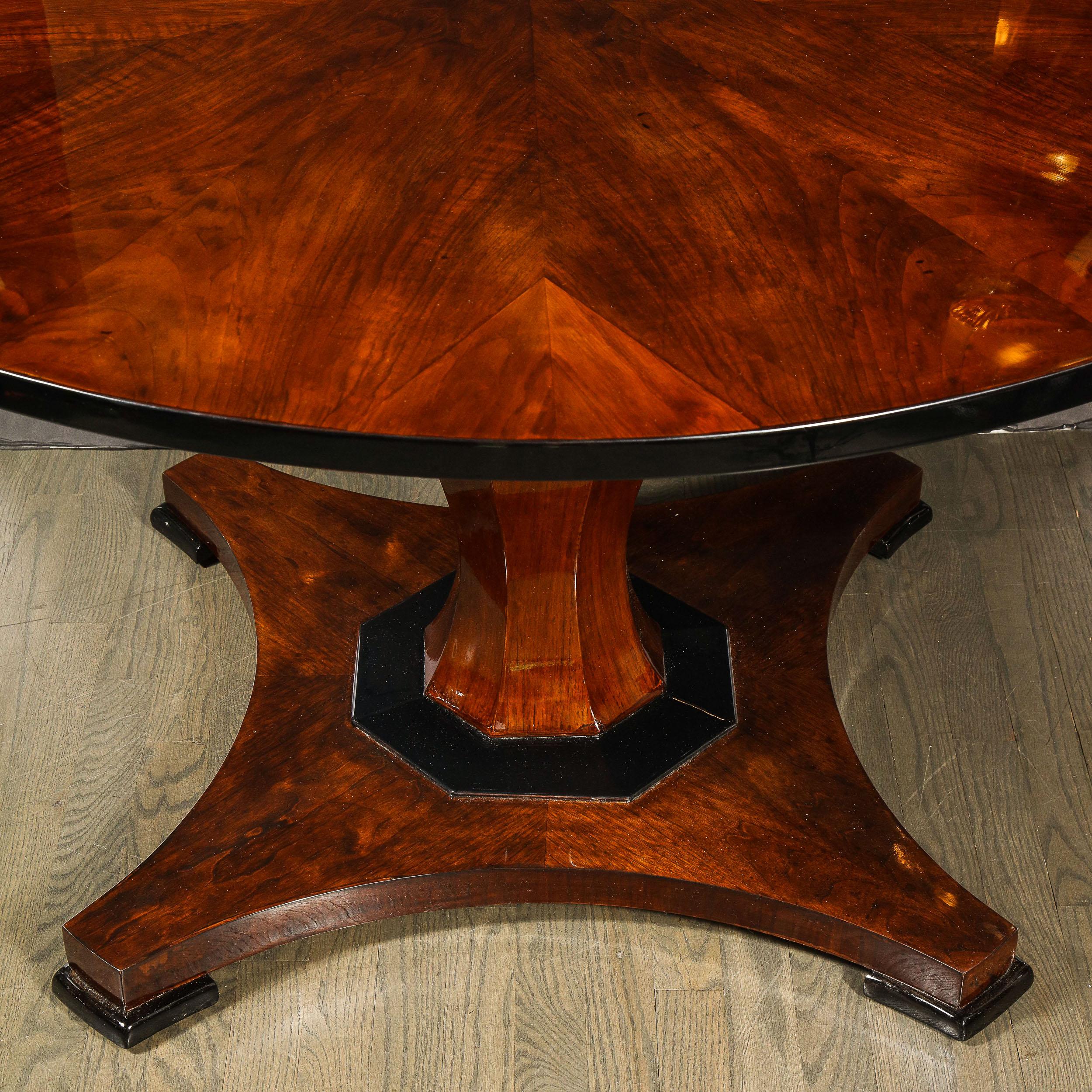 This elegant Art Deco dining/ center table was realized in France, circa 1930. It features a circular top in bookmatched walnut top an undulating faced body also in bookmatched walnut; and a streamlined base with an hexagonal black lacquer