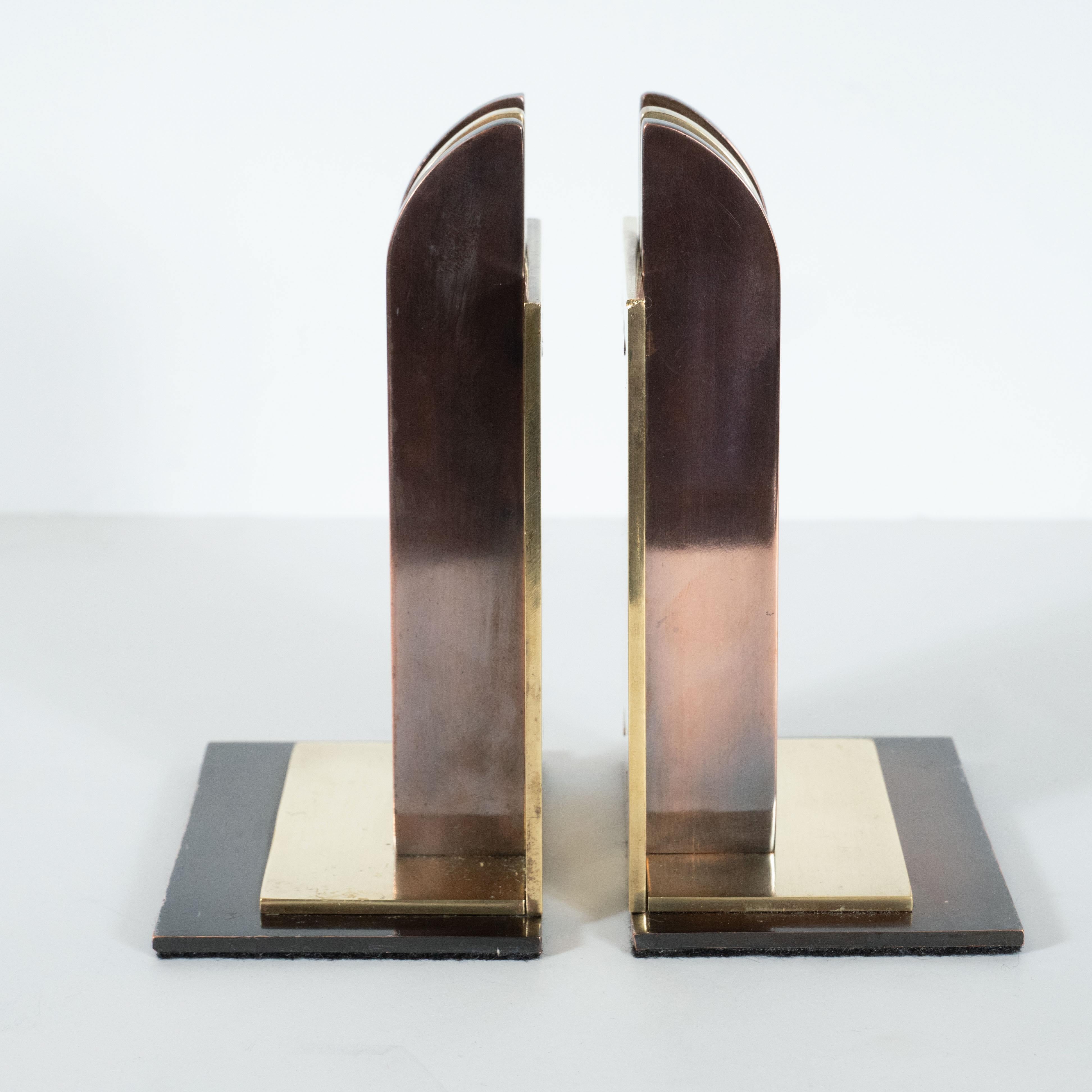 This stunning pair of Machine Age Art Deco bookends were realized by the illustrious 20th century designer Walter Von Nessen for Chase Co. in America, circa 1930. It features a skyscraper style base composed of a rectangular copper base with a brass