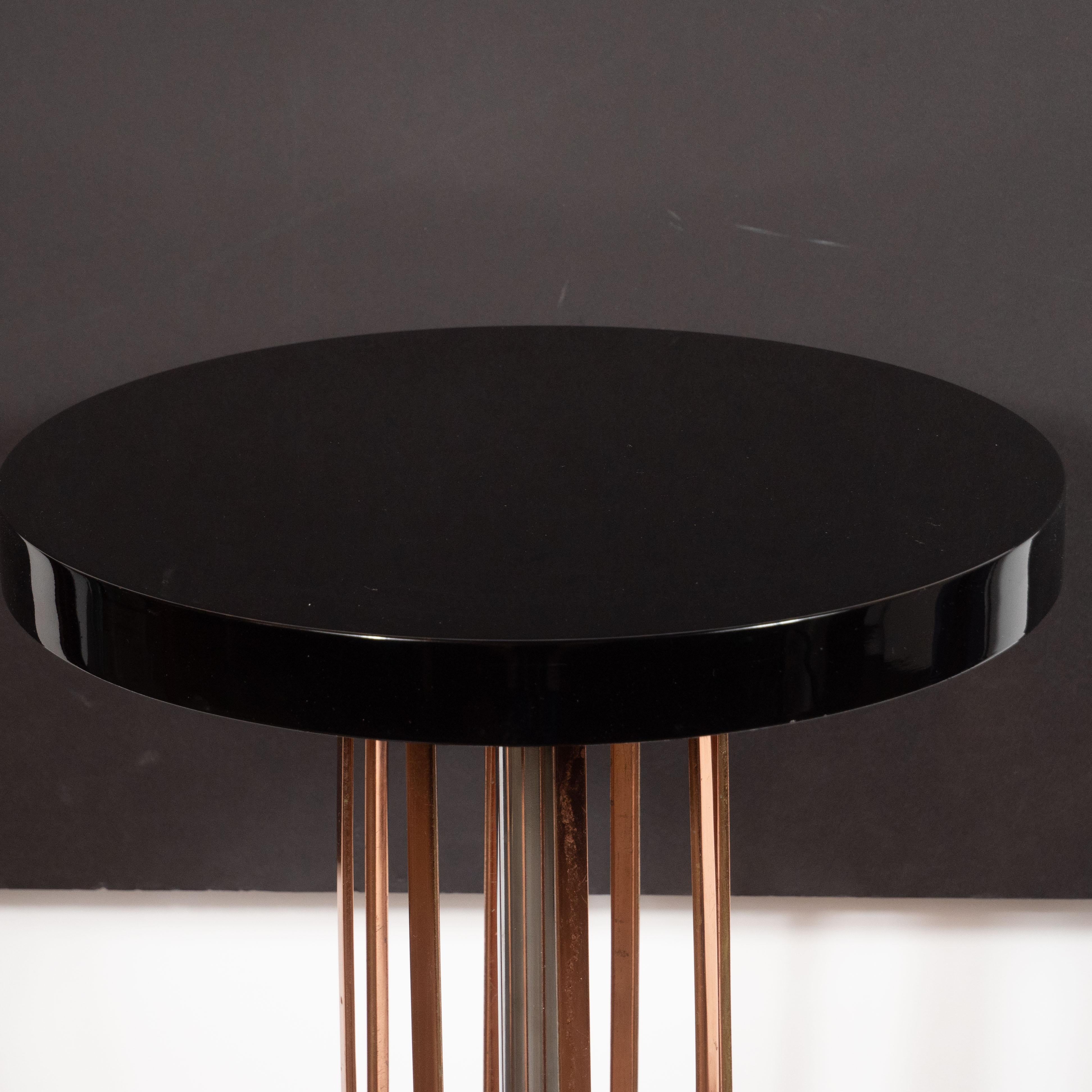 This stunning side/ drinks table was realized in the United States, circa 1935. It features a circular skyscraper chrome base with four streamlined reeded black enamel feet peaking out from beneath. There is a circular copper plate secured to the