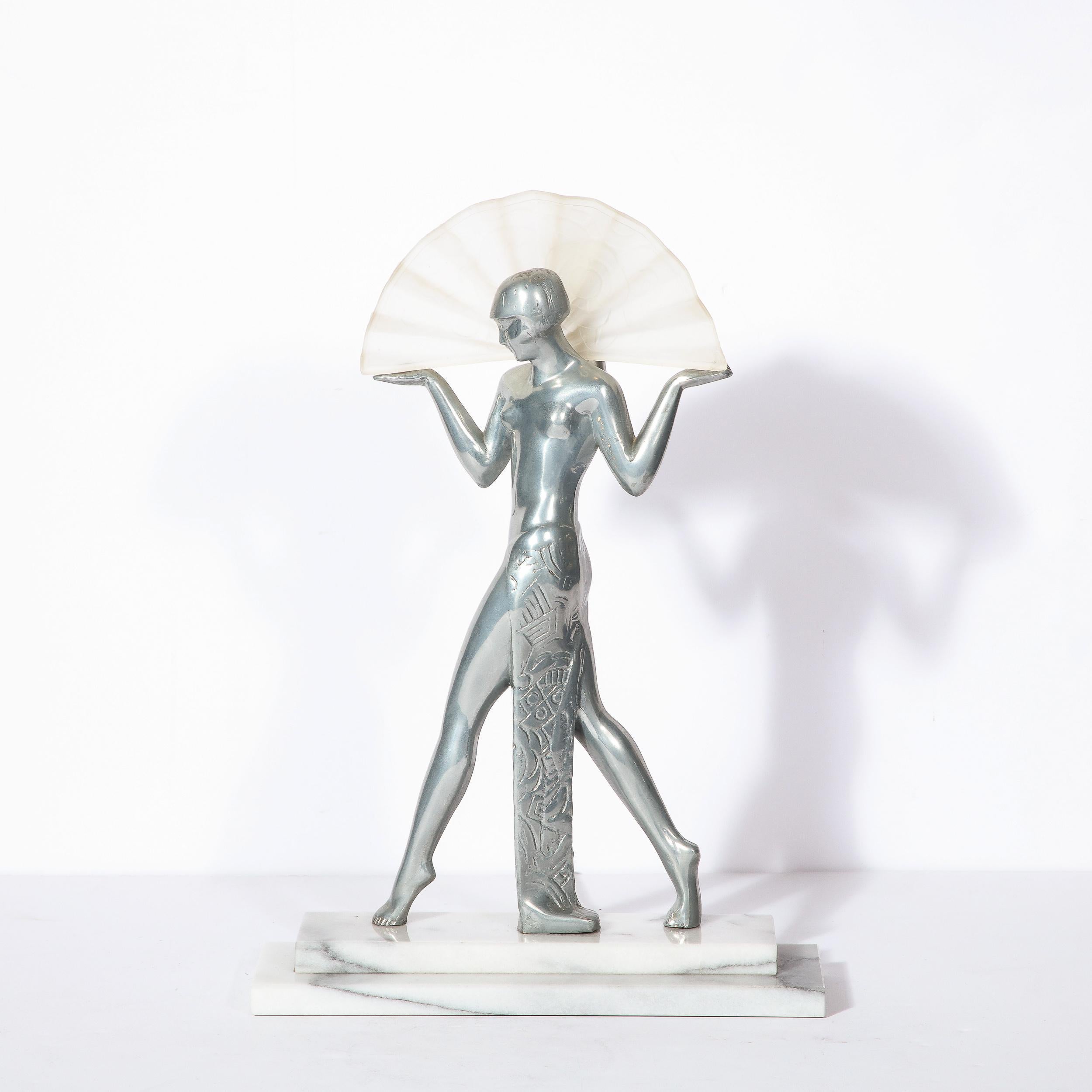 This elegant Art Deco revival table lamp was realized in the United States during the 20th century. It features a classic female flapper figurine realized in lustrous pewter strutting forward on her toes, her palms extended outwards and facing