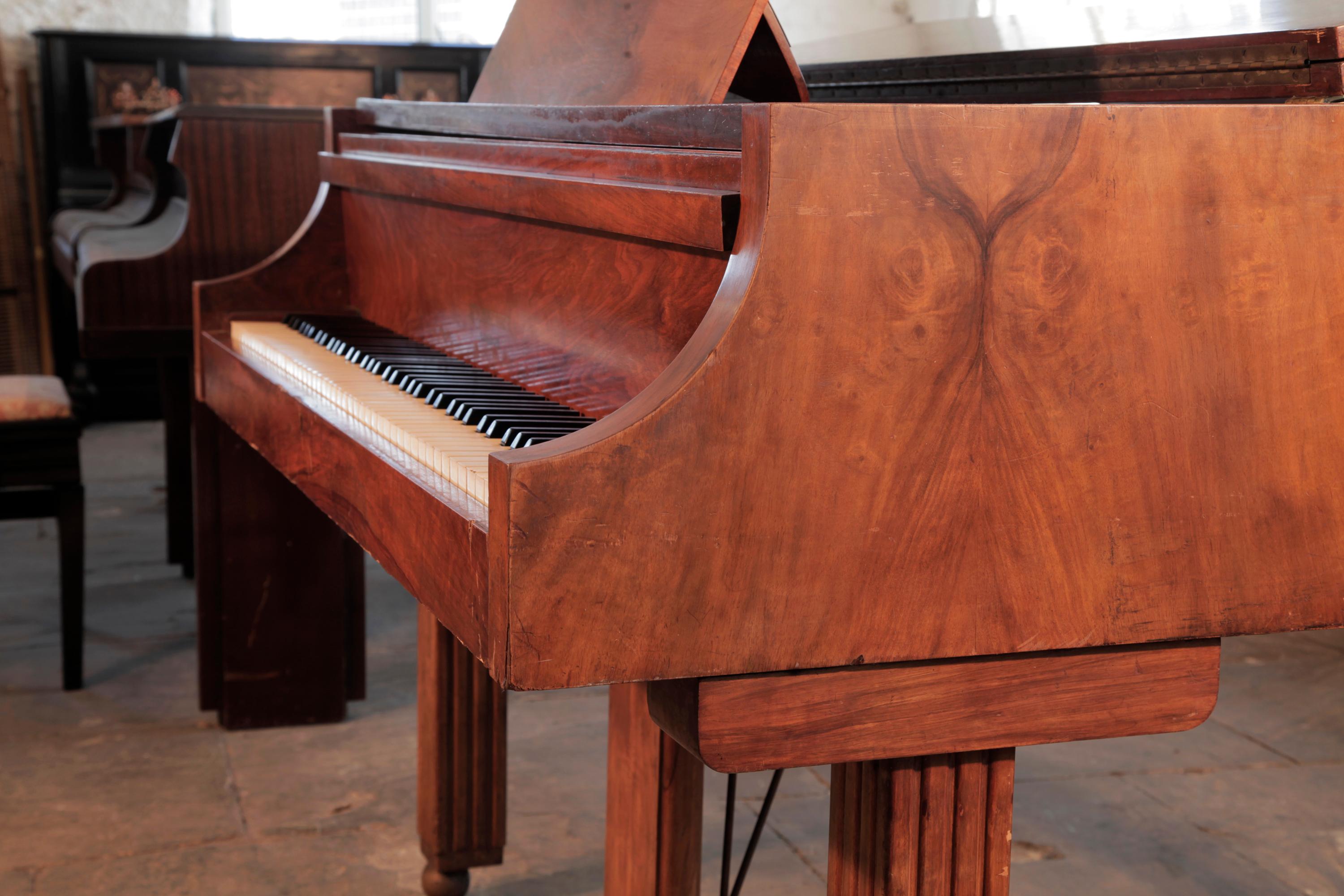 Piano à queue Strohmenger de style Art déco, 1945, avec un meuble en noyer figuré poli, assorti aux livres, et des ferrures en laiton. La joue piano, très arquée, se termine par une coupe carrée anguleuse. Le piano a des pieds carrés et cannelés