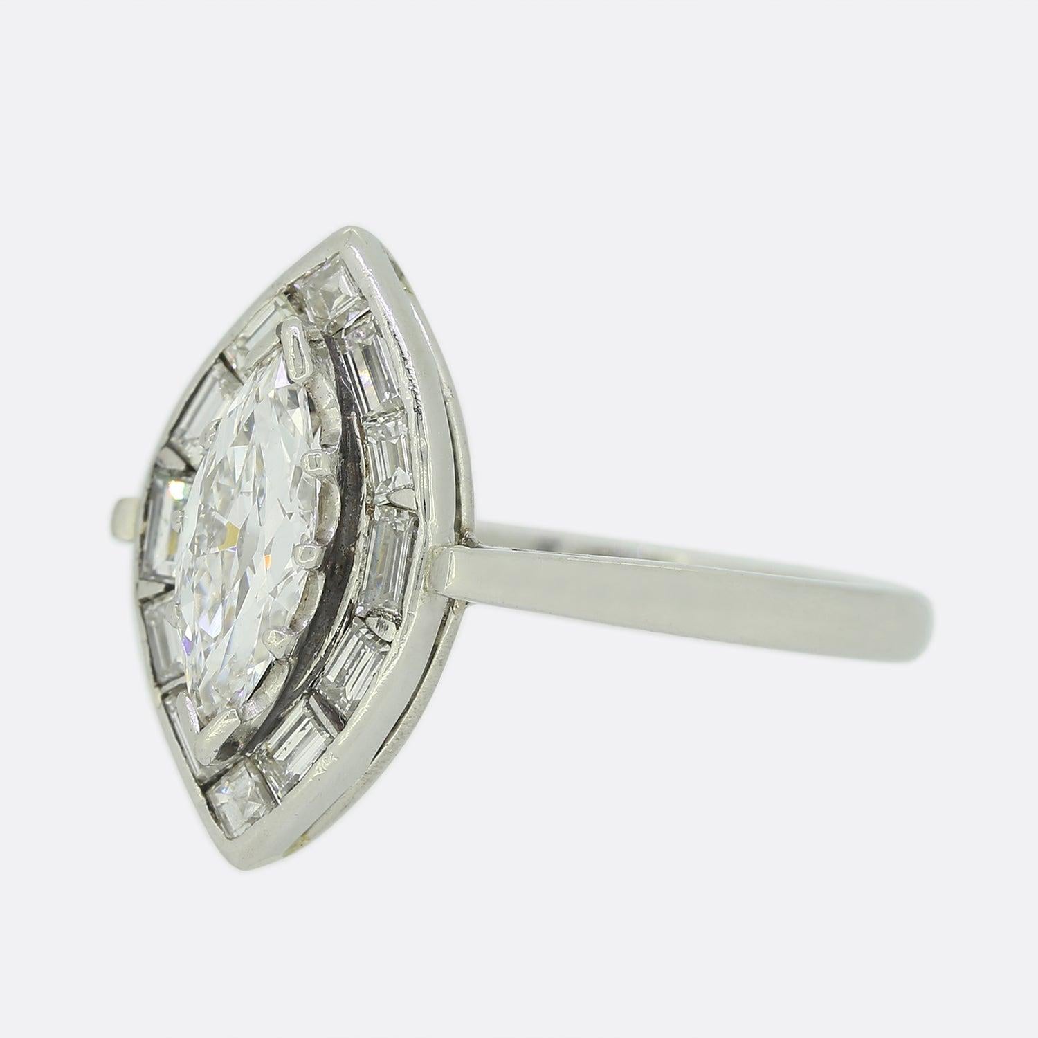This is a platinum diamond halo ring. The focal point of this ring is a 0.60 carat old marquise cut diamond set in a claw setting with a border of ten baguette cut diamonds in a modern Art Deco style design. The ring has been crafted in platinum