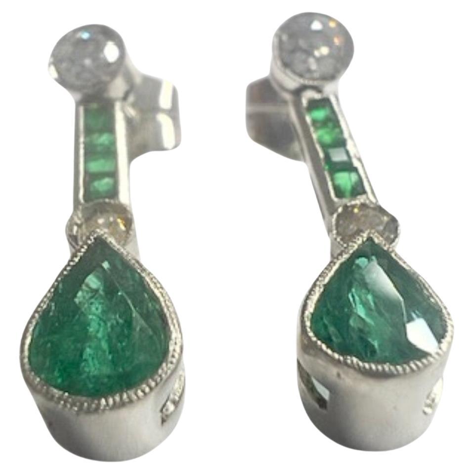 These Art Deco-style earrings are crafted in platinum 950 and feature Diamonds and Emeralds. They have a combined weight of 3.74 grams. 
The Diamonds are antique-cut, totaling 0.60 carats, with SI-VS clarity and H-I color. 
The center emeralds are