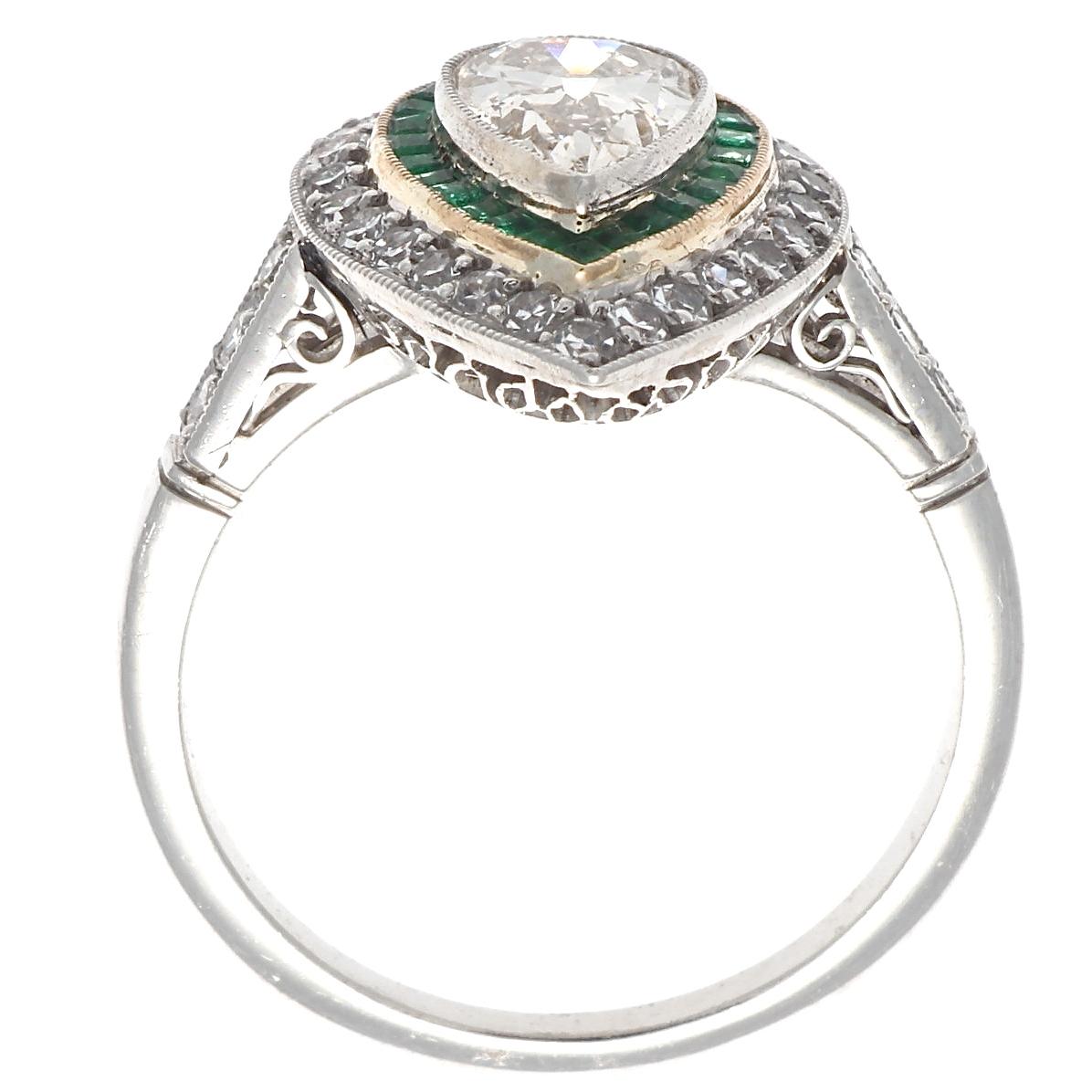 The prettiest vintage pear shaped diamond is the star of this ring show. This Art Deco inspired design features a gorgeous pear shaped diamond just under 1 carat. Adorned by 31 glittering single cut diamonds and 26 calibré emerald cut emeralds, this