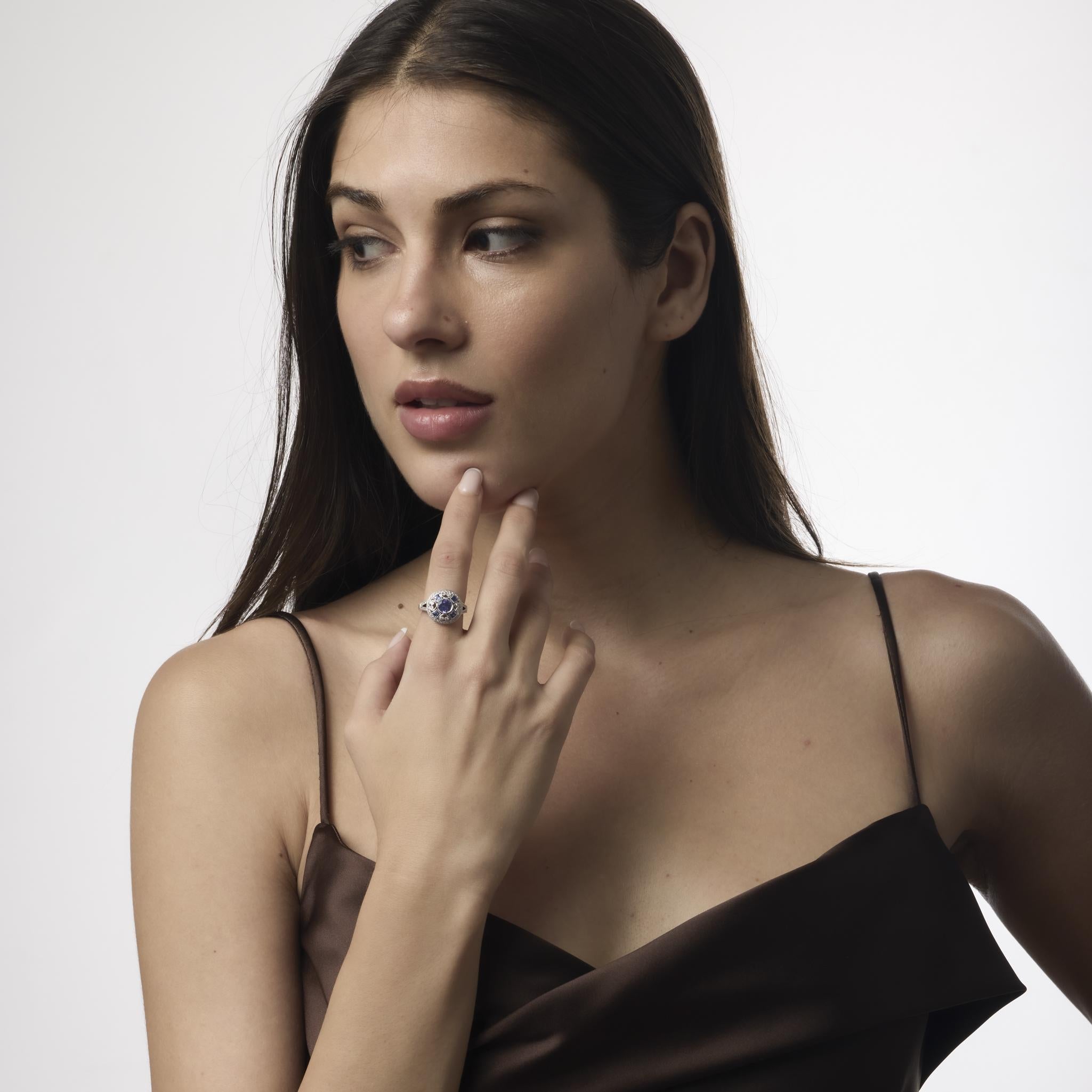 Un llamativo anillo de platino con una tanzanita redonda de 1,10 quilates, enmarcada por zafiros de gran calibre y 64 brillantes diamantes de color E-F y claridad VS de estilo Art Déco.