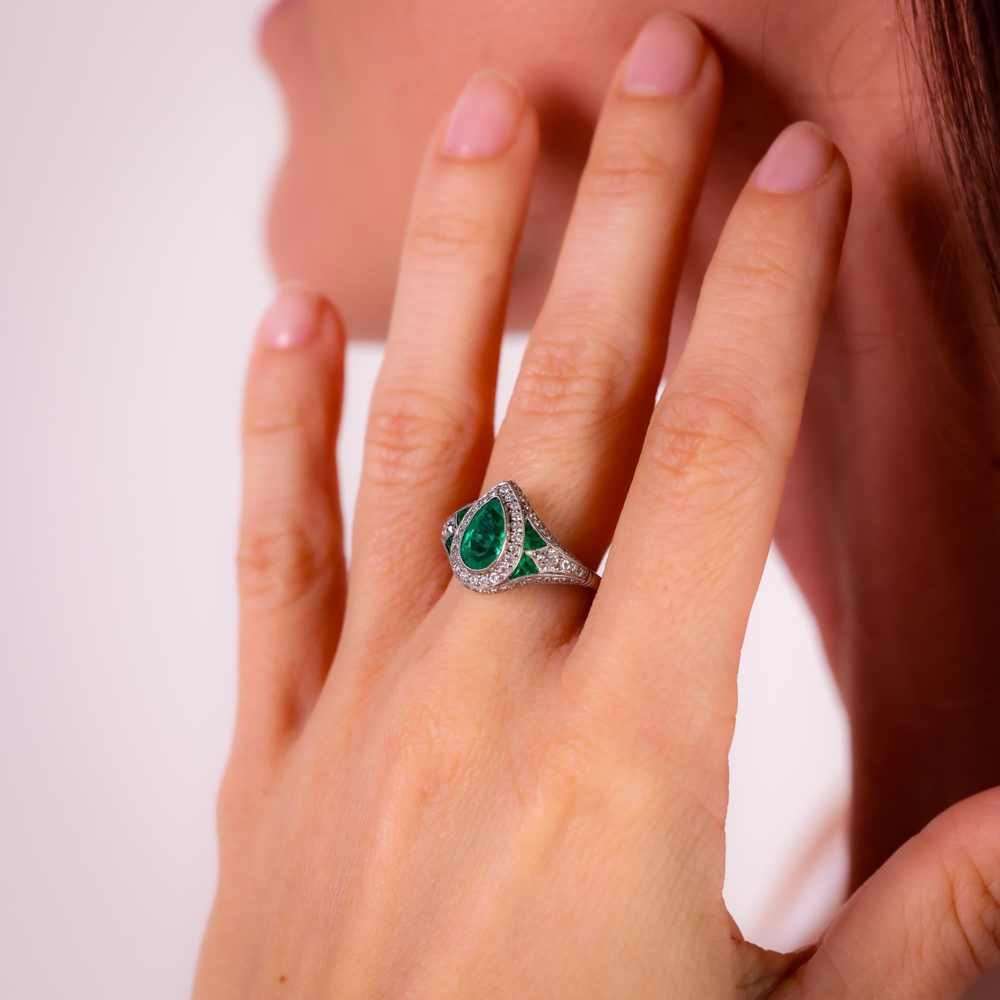 This modern Art Deco-inspired platinum ring features a 1.15 carat pear shape emerald, framed by sparkling old European cut diamonds and vivid calibre cut emeralds for timeless elegance.

Center stone: Pear shape emerald 
Weight: 1.15 carat
Accent