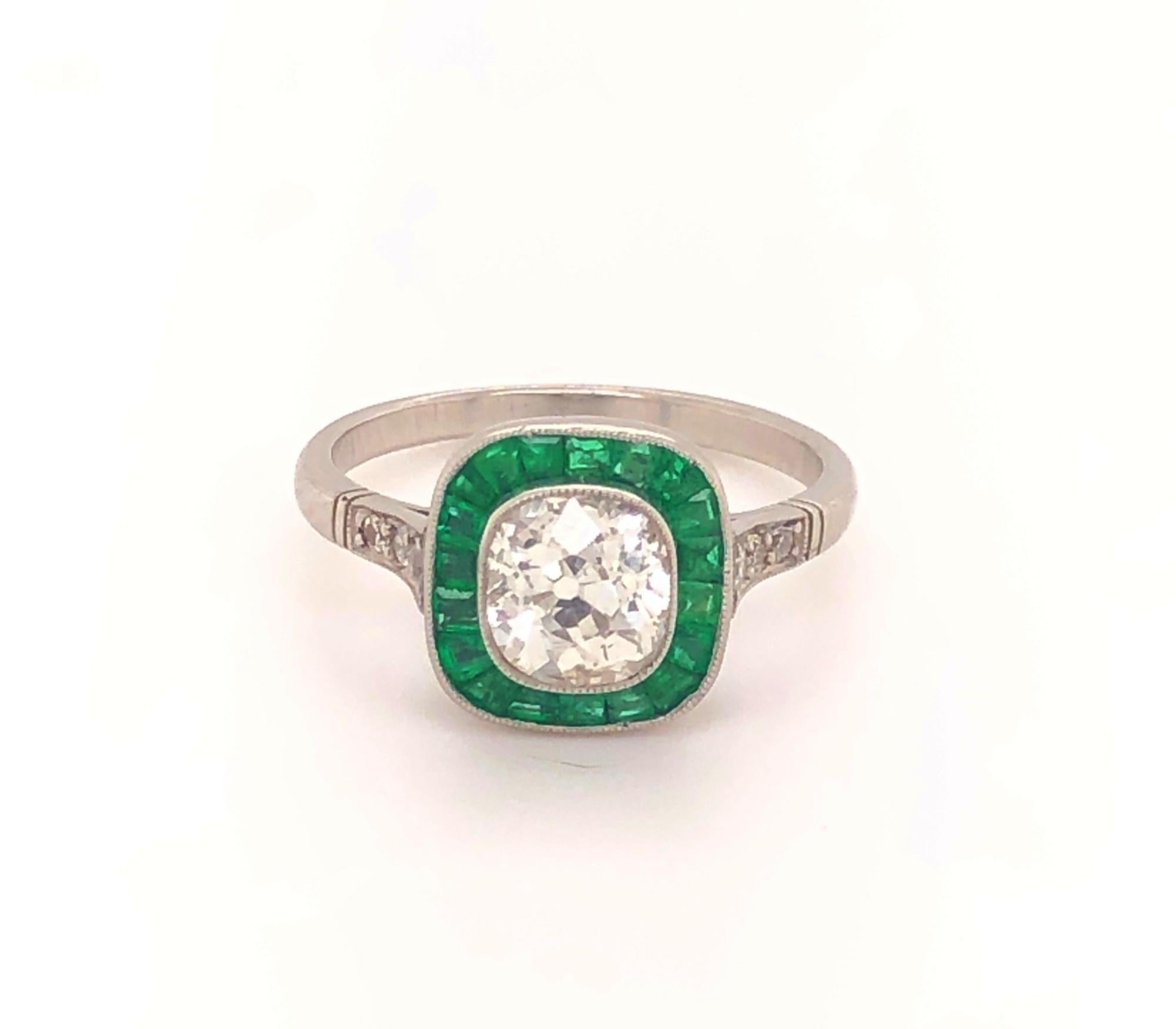 Art Deco Style 1.22 Old Mine Cushion Cut Diamond Emeralds Platinum Ring. The center diamond is a white sparkly old mine cushion cut J color SI-1 clarity. The halo has 20 natural caliber cut emeralds. On each shoulder are three diamonds. The gallery