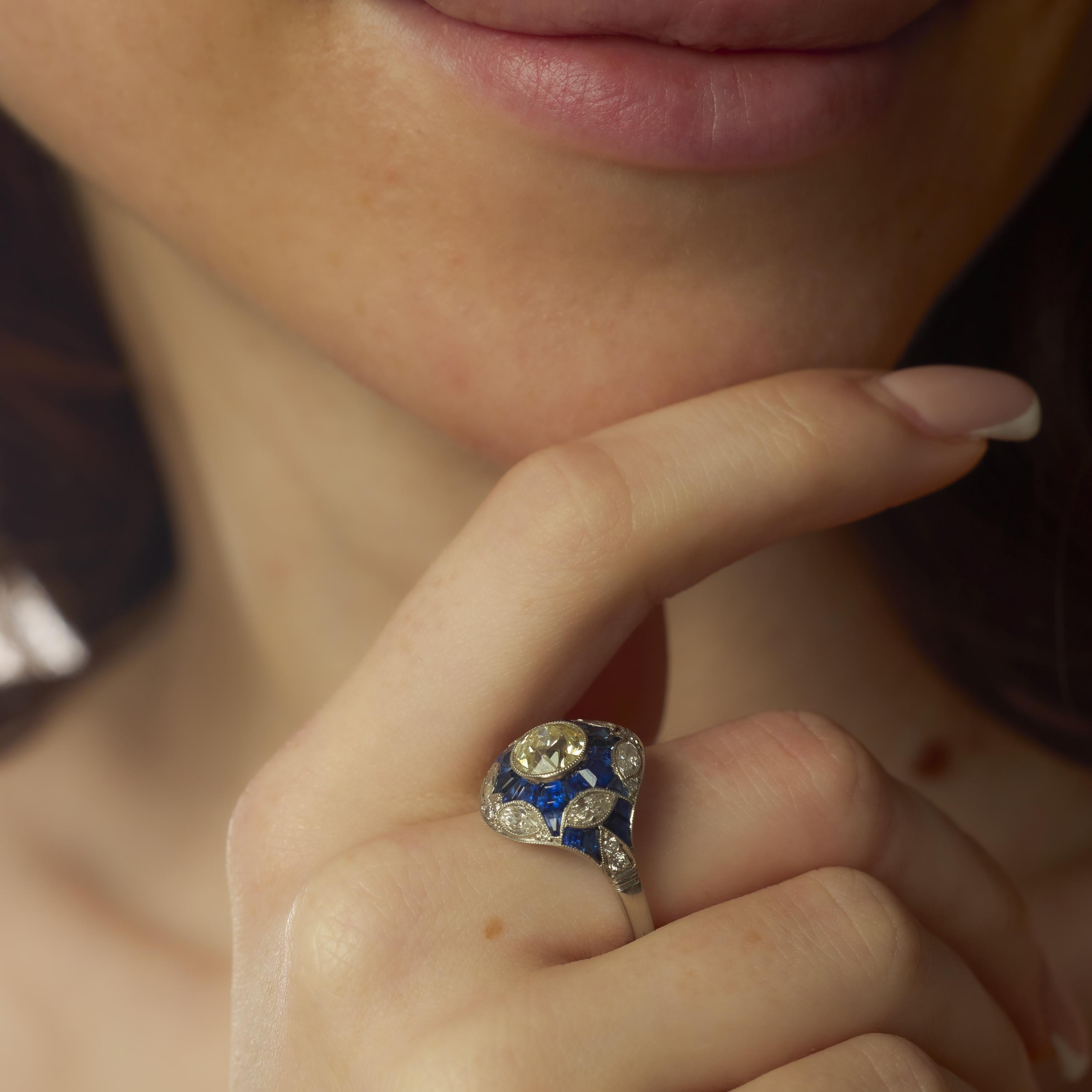 Cette bague en platine d'inspiration Art déco présente en son centre un diamant de taille européenne ancienne de 1,27 carat, rayonnant d'une douce chaleur et d'une clarté VS. Le diamant est entouré de seize diamants brillants de taille marquise et