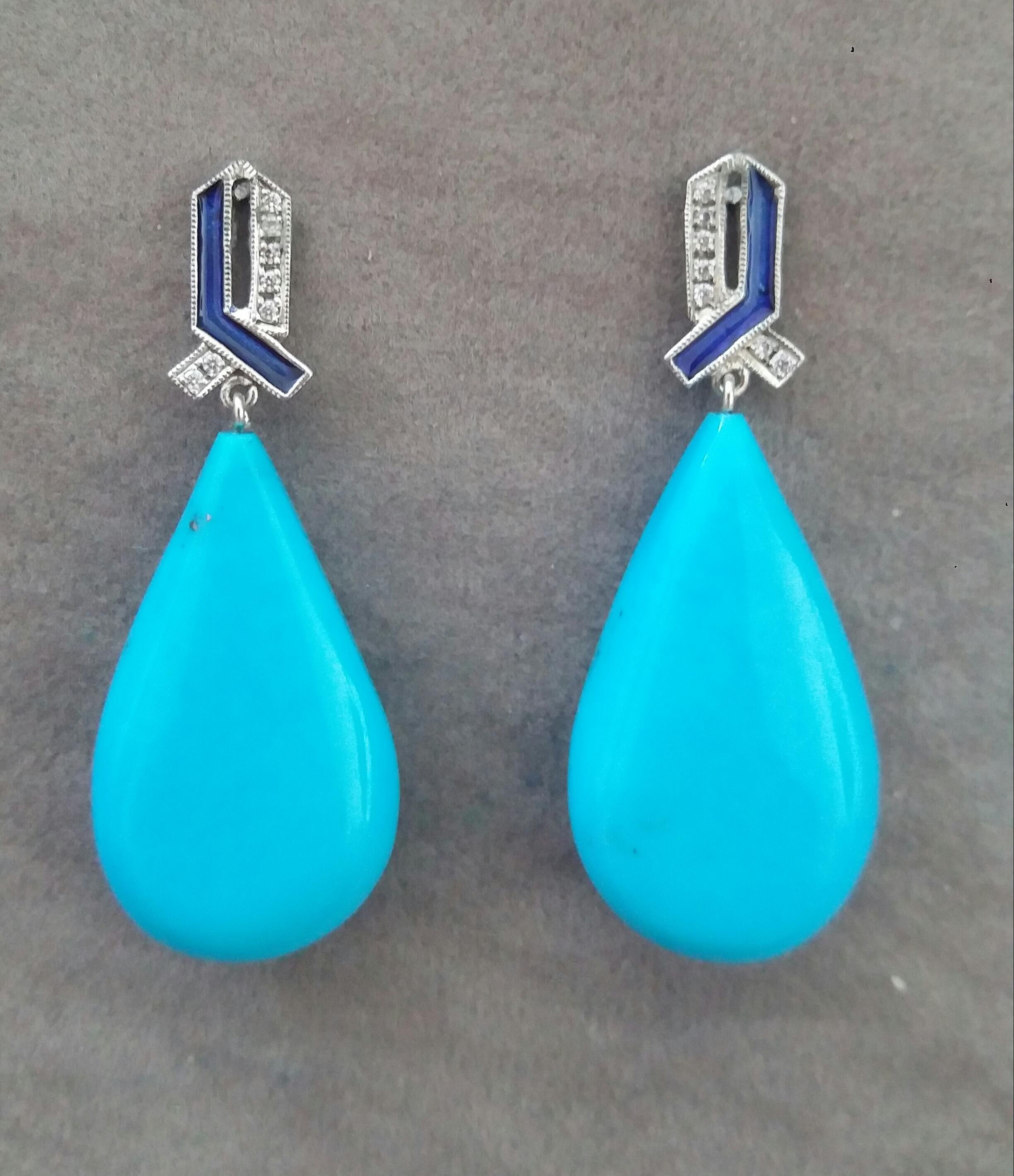 In questi orecchini fatti a mano in stile Art Deco 2  gocce lisce di turchese naturale di buona qualità che misurano 17 x 30 mm. sono sospese a 2 elementi in oro bianco 14 kt.  con 16 diamanti rotondi a taglio pieno e smalti blu.
Questi orecchini