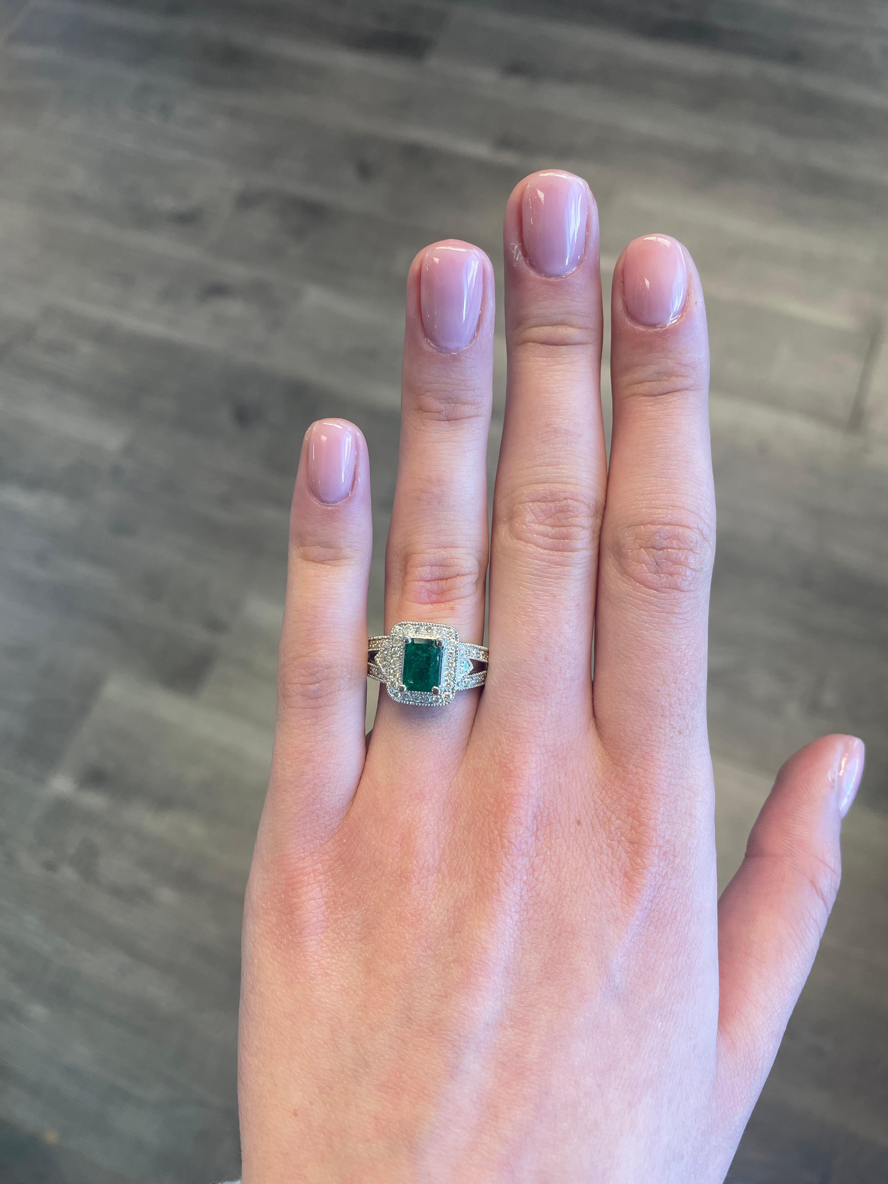 Art Deco inspired emerald and diamond halo ring with split shank, millgrain filigree work.
1.73 carats total gemstone weight.
1.03 carat emerald cut emerald, apx F2. Complimented by 0.70 carats of round diamonds, approximately I/J color and SI
