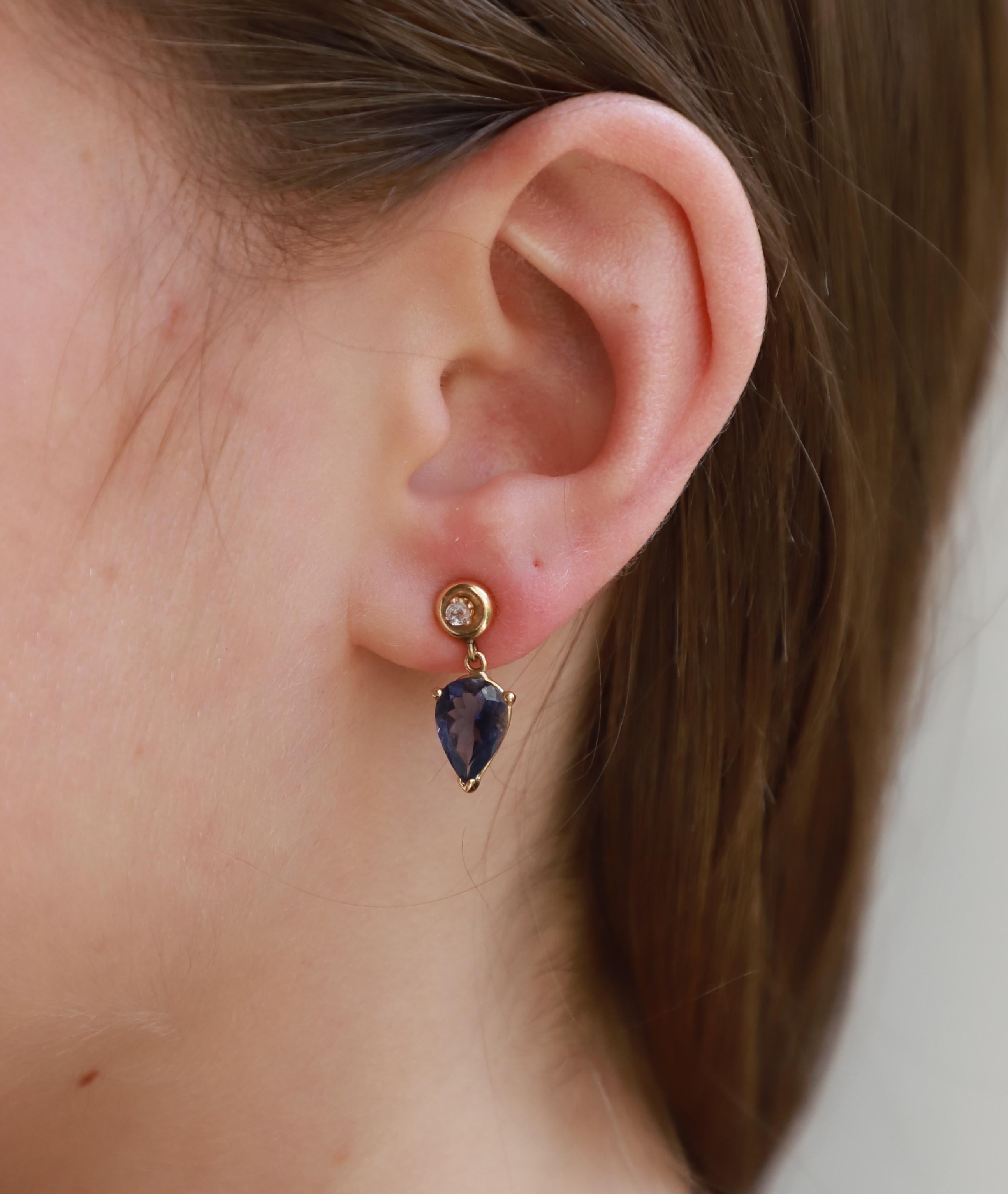 Rossella Ugolini Design Collection, Classy drop earrings handcrafted in 18 karat yellow gold and  embellished with a deep Indigo Blue of Iolite stone and 0.10 karat Grey Diamonds.
A simple design earring with the tip of the drop-shaped Iolite stone