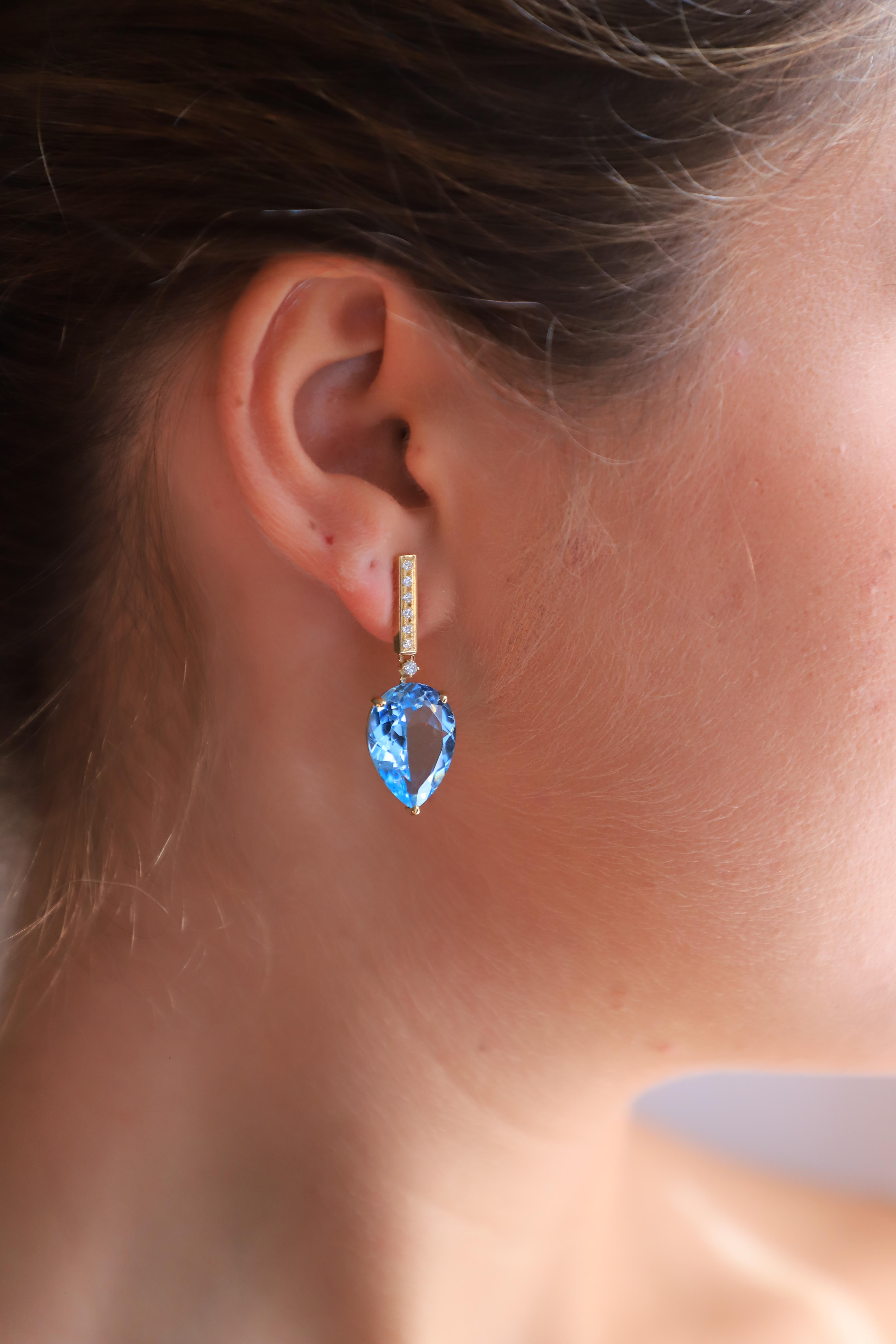 Introducing our exquisite Limited Edition By Rossella Ugolini Design, Art Deco Style Bold Dangle Earrings.
A captivating fusion of 18 Karat Yellow Gold, Blue Topaz, and 0.12 Carats White Diamonds. 
These earrings are a true statement piece, designed
