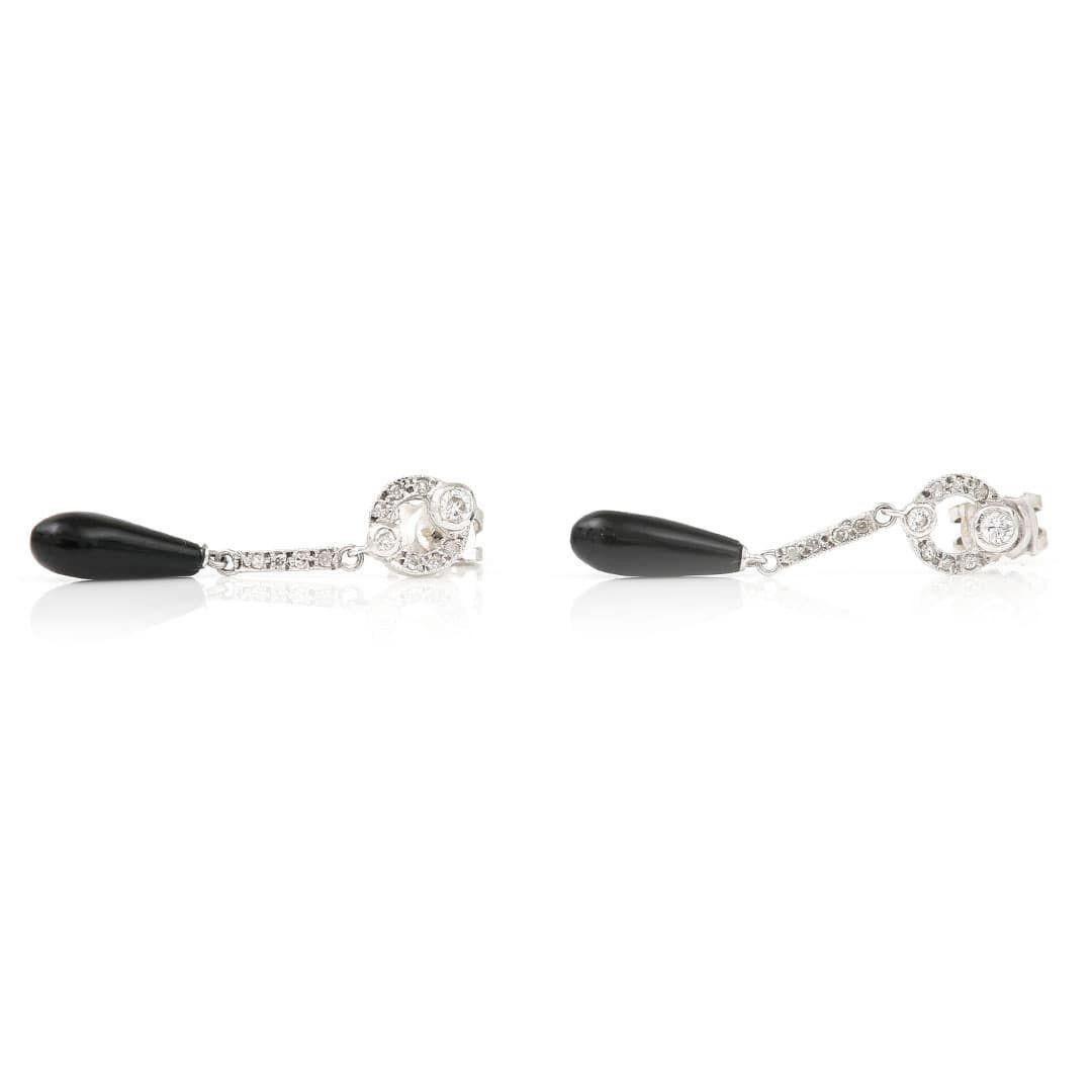 A delightful pair of Art Deco style black onyx and diamond 18ct white gold drop earrings. The tear drop cabochon cut black onyx measuring approx 12mm x 4.5mm is fully articulated to capture that roaring 30’s style. The drop is suspended from a hoop