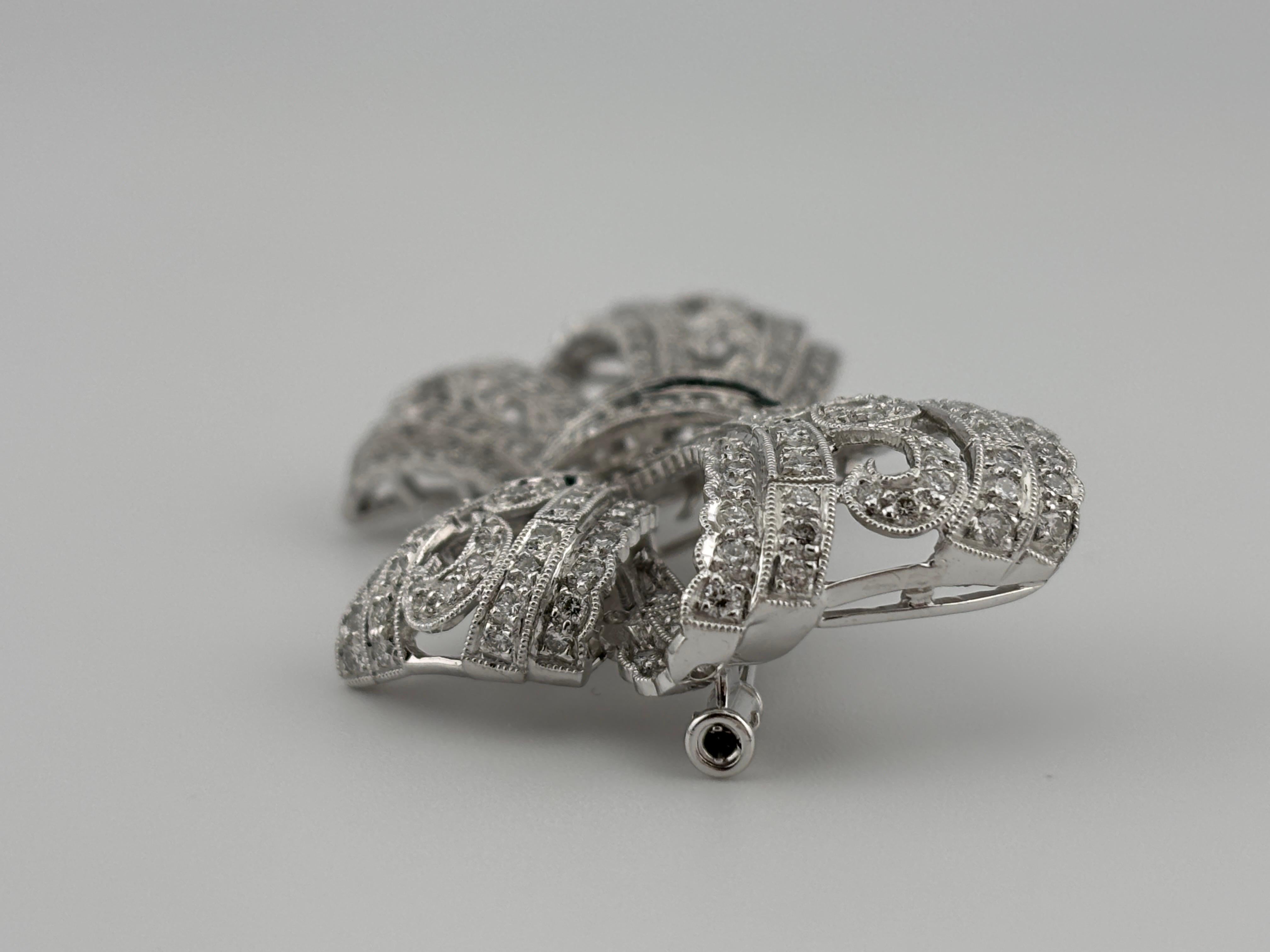 This exquisite Art Deco-style 18k white gold diamond bow brooch is a true testament to timeless elegance and craftsmanship. The intricate design features a stunning bow shape, adorned with a sparkling array of high-quality diamonds that catch the