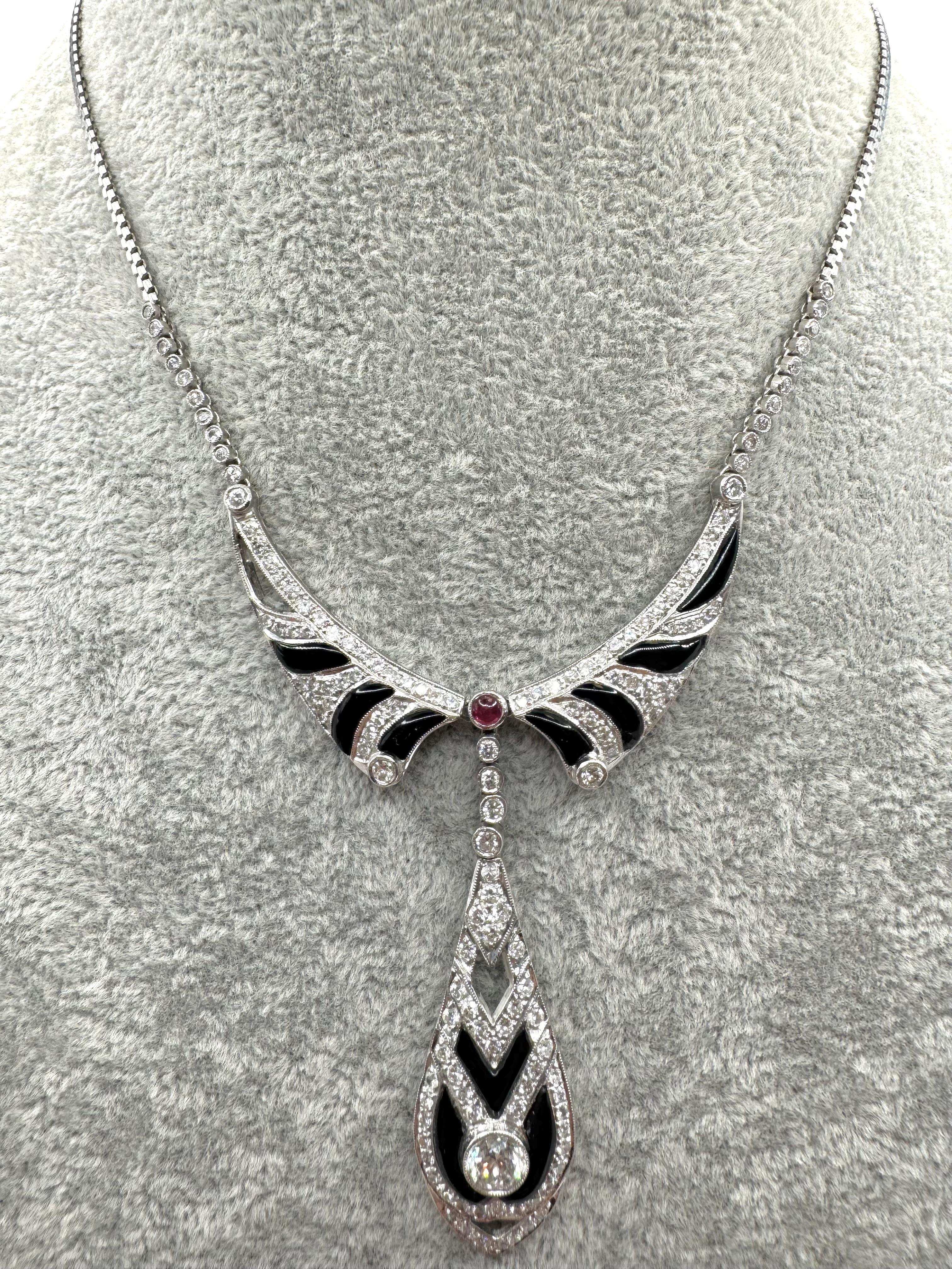 D'une élégance frappante et d'un style vintage audacieux, ce collier d'inspiration Art of Vintage est réalisé en or blanc 18 carats et présente un jeu spectaculaire d'onyx, de diamants et de rubis. La pièce centrale présente un rubis rond vibrant
