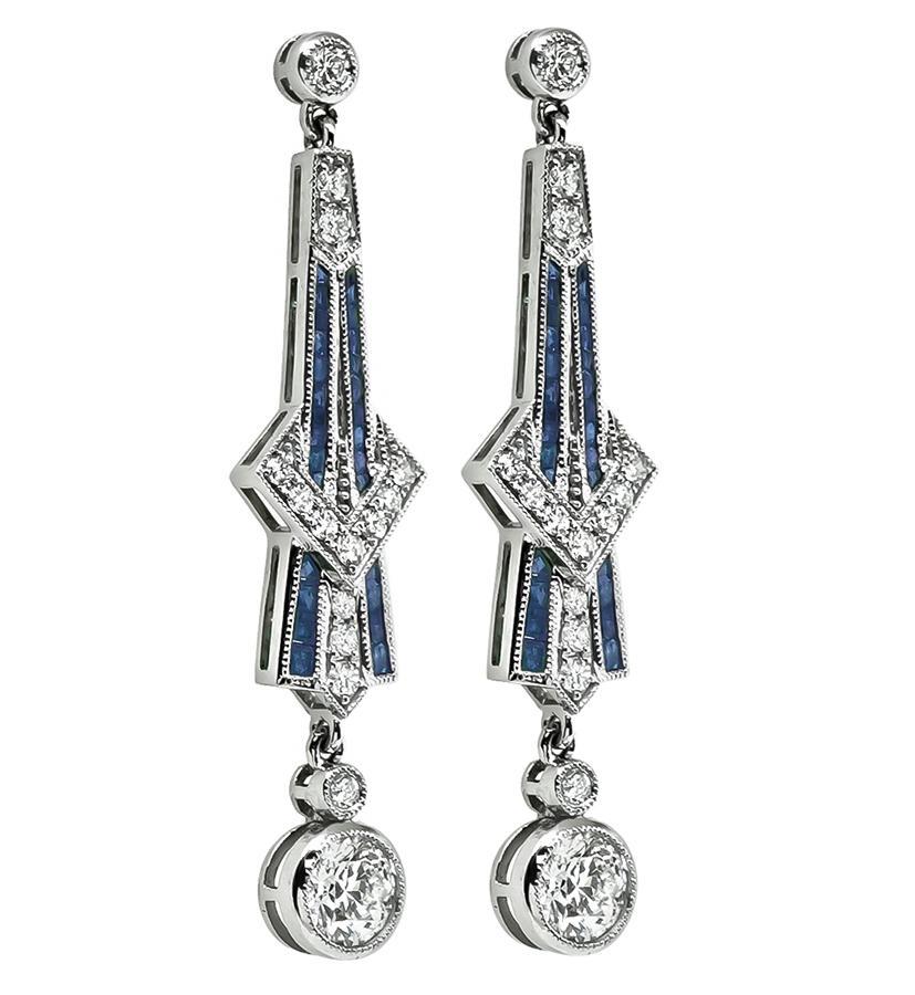 This is a stunning pair of platinum drop earrings. The earrings feature sparkling round cut diamonds that weigh approximately 1.90ct. The color of these diamonds is G with VS2-SI1 clarity. The diamonds are accentuated by lovely square cut sapphires