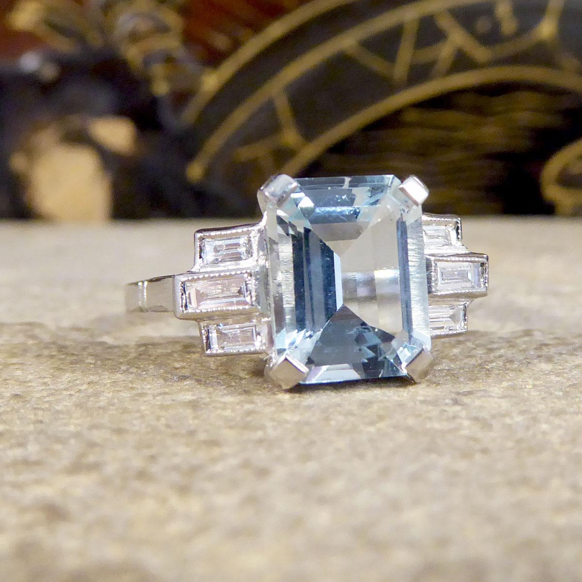 This ring is featuring a lovely Emerald cut light blue Aquamarine gemstone weighing 2.00ct in a four claw setting. Accompanied by three Baguette cut Diamonds making a 