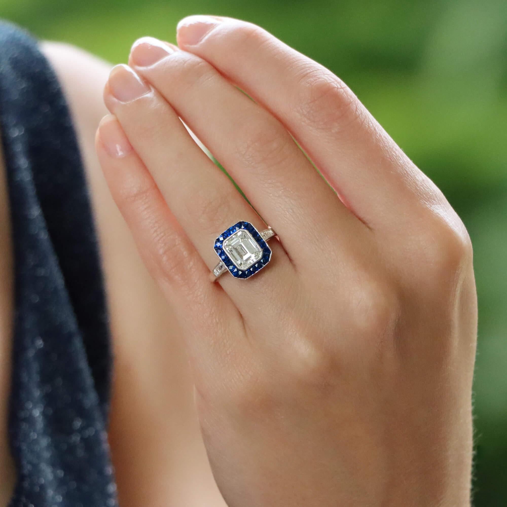 A beautiful Art Deco inspired emerald cut diamond and sapphire target ring set in platinum.

The ring is predominantly set with an extremely sparkly 2.03 carat emerald cut diamond which is securely bezel set to centre. Surrounding the central