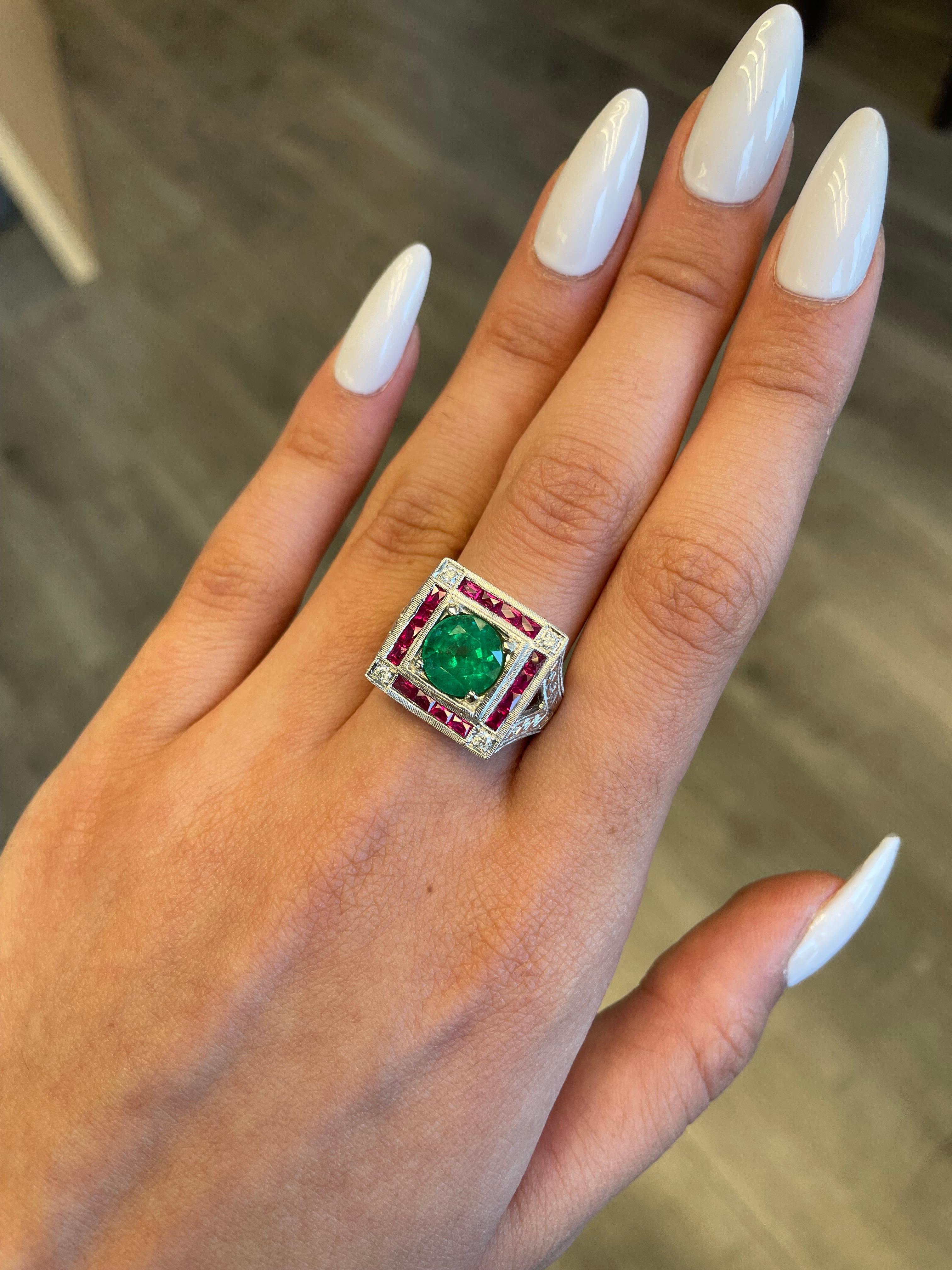Lovely vintage inspired emerald with sapphires and diamond ring.
2.15 carat round emerald apx F2 complimented with 1.21ct of french cut rubies heat and 0.10ct of round brilliant diamonds. Approximately G/H color and SI clarity. 18-karat white gold
